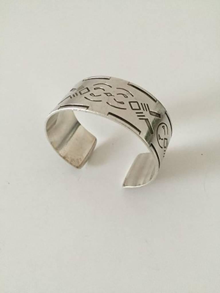 Georg Jensen Bangle, Sterling Silver
Wide Cuff Design with Native American Motif #64. Designed by Harald Nielsen. Dates to after 1945. Measures 6 cm dia / 2 23/64 in. Weighs 43 g / 