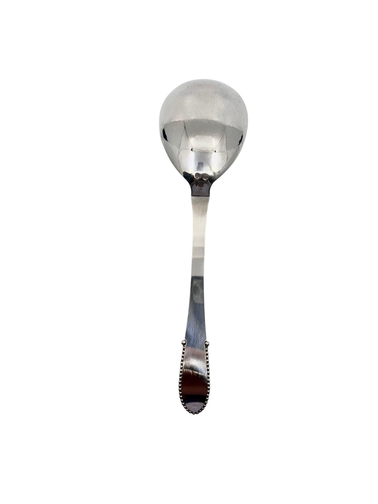 A large sterling silver Georg Jensen serving spoon, item #113 in Beaded pattern, design #7 by Georg Jensen from 1916.

Additional information:
Material: Sterling silver
Styles: Art Nouveau
Hallmarks: early 1928 date stamp, Georg Jensen 830s