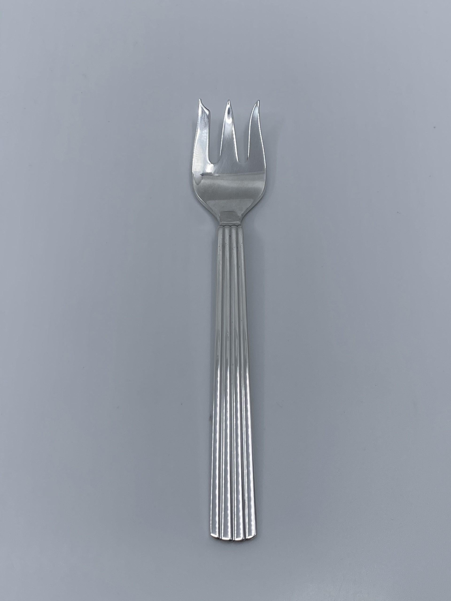 04A Georg Jensen sterling silver cake fork, item #043 in the Bernadotte pattern, design #9 by Sigvard Bernadotte from 1939.

Additional information:
Material: Sterling silver
Styles: Art Deco
Hallmarks: With Georg Jensen hallmark, made in