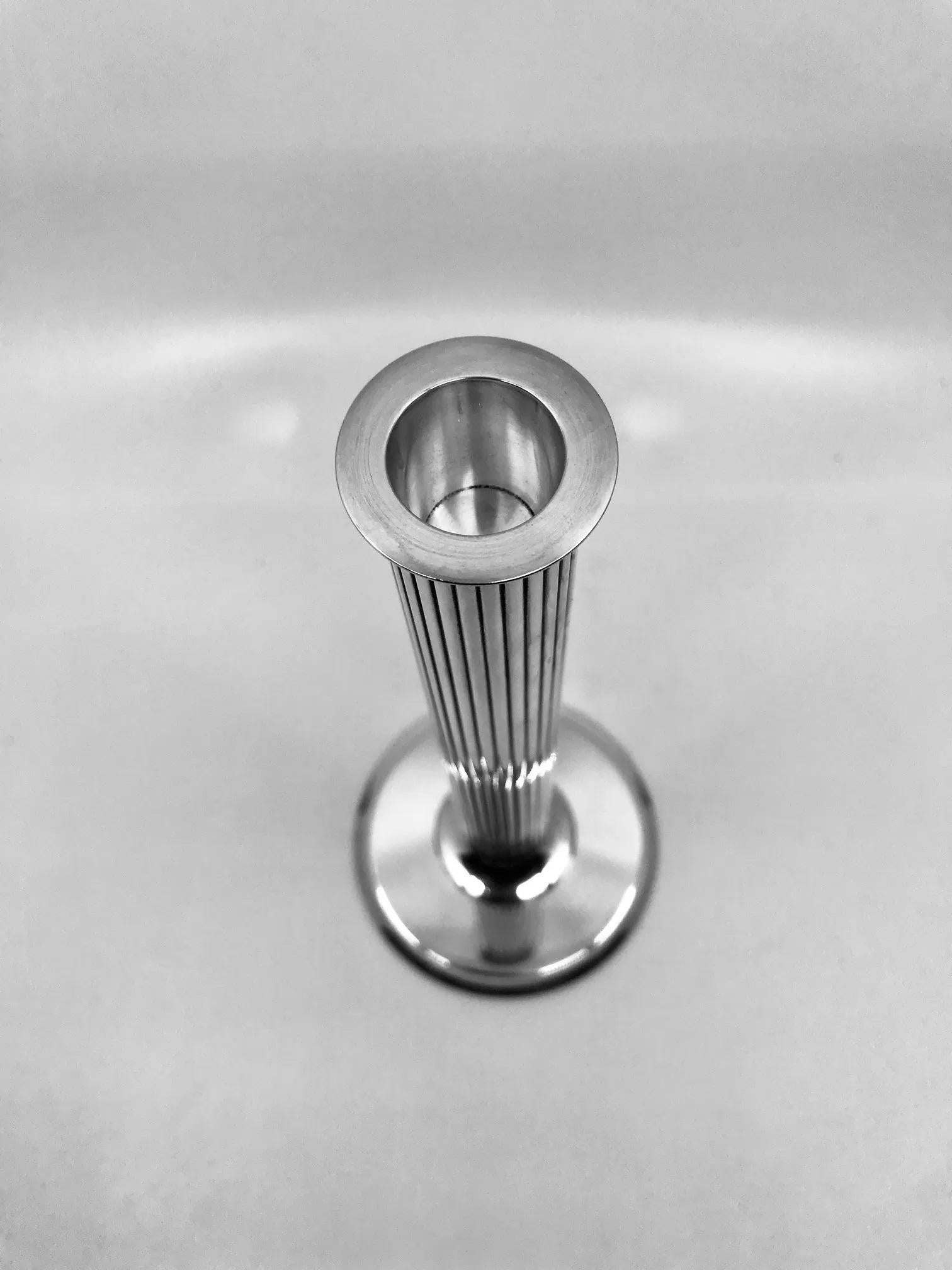 A pair of vintage sterling silver Georg Jensen candlesticks, design #855B by Sigvard Bernadotte dating back to 1938. Each candlestick features a round tiered foot connected to a long, hand-chased linear design column. The sconce is elegantly crafted