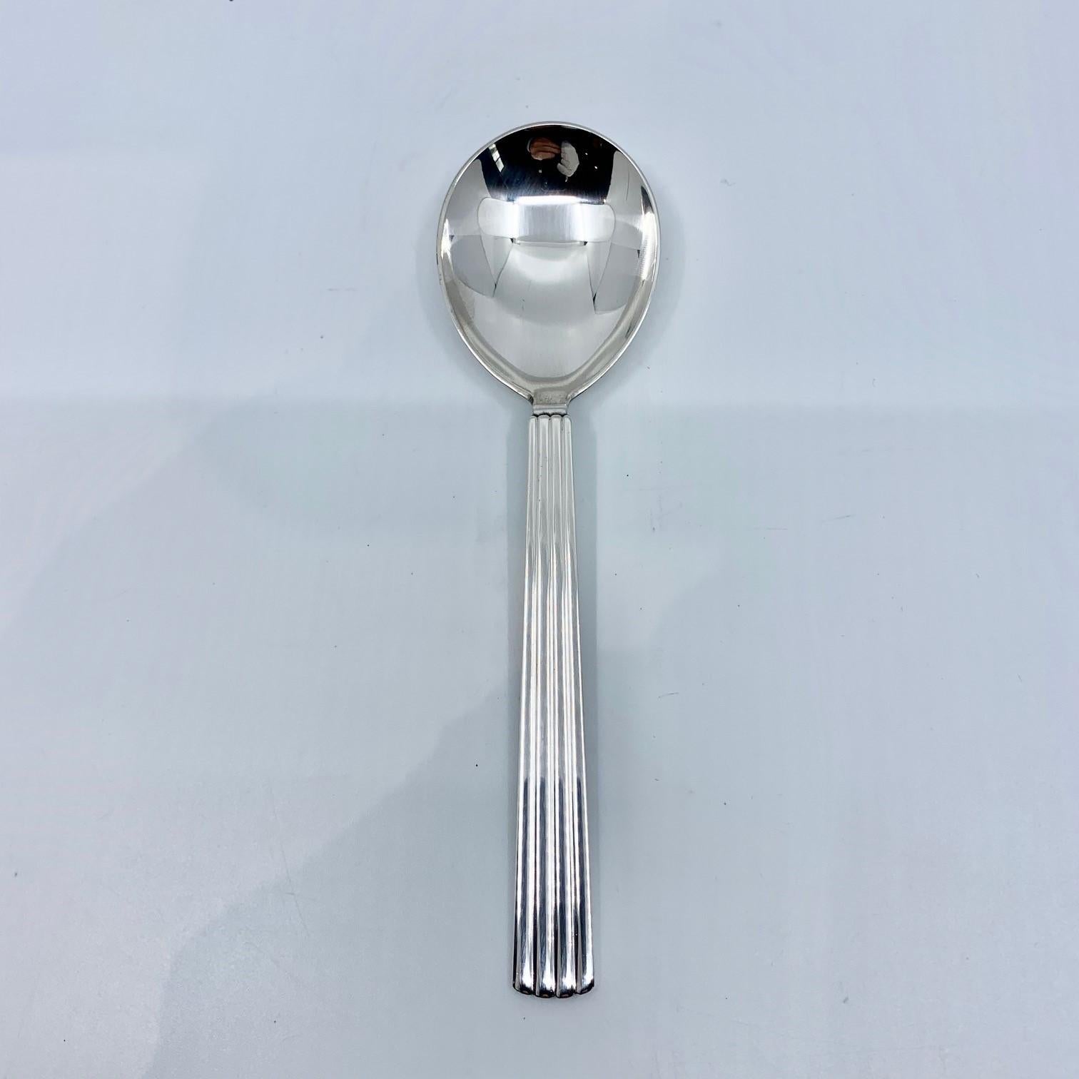A Georg Jensen sterling silver jam spoon, item 163 in the Bernadotte pattern, design #9 by Sigvard Bernadotte from 1939.

Additional information:
Material: Sterling silver
Style: 
Hallmarks: With Georg Jensen hallmark, made in Denmark.
Dimension: 