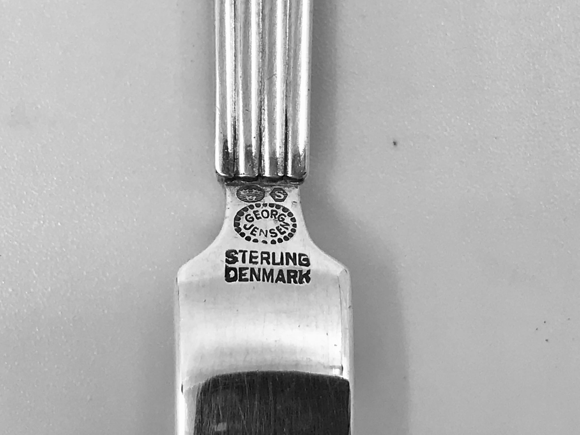 Sterling silver Georg Jensen lemon fork, item 146 in the Bernadotte pattern, design #9 by Sigvard Bernadotte from 1938.

Additional information:
Material: Sterling Silver
Style: Art Deco
Hallmarks: With Georg Jensen hallmark, made in