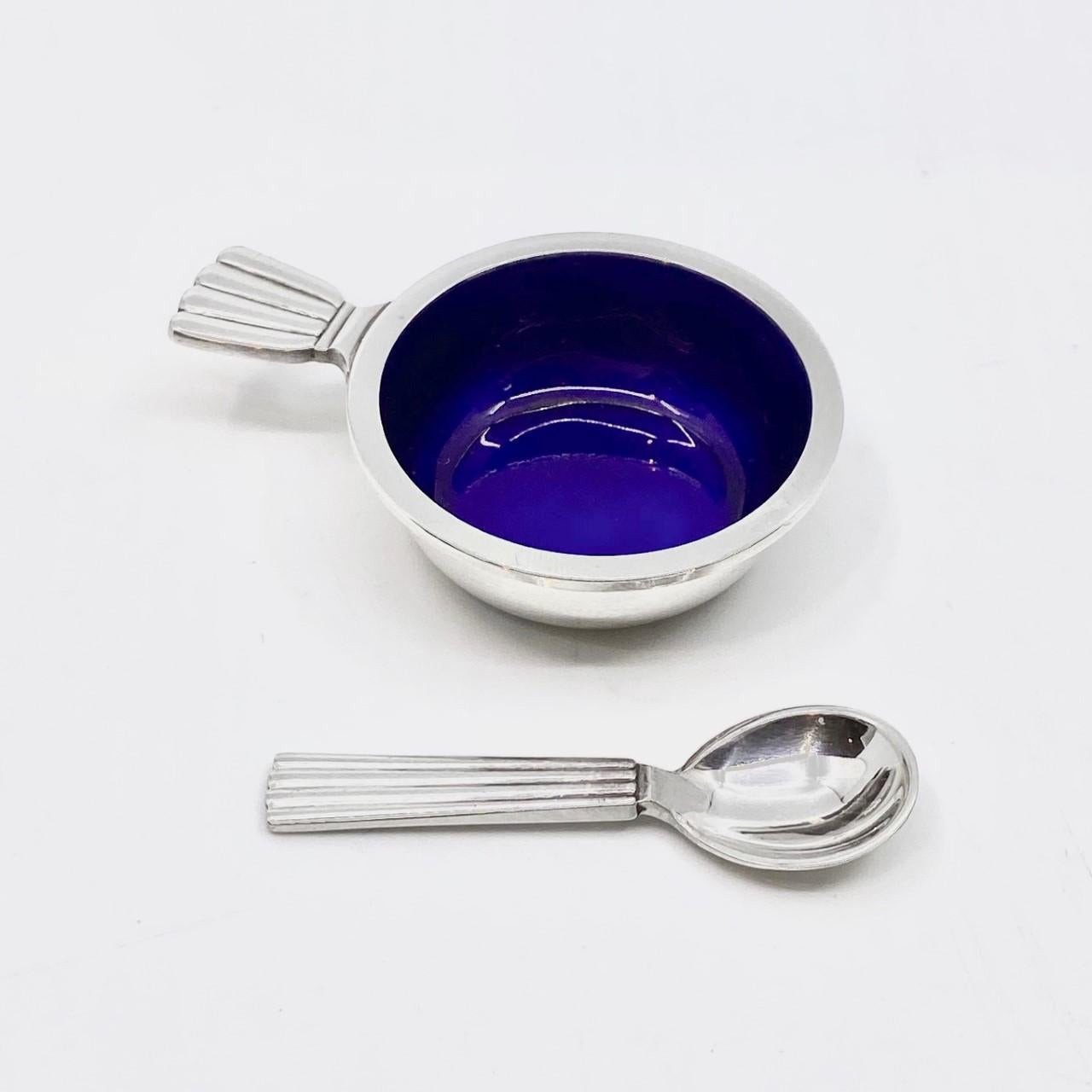 Georg Jensen sterling silver salt cellar with blue enamel and salt spoon, items #102 & #103 in the Bernadotte pattern, design #9 by Sigvard Bernadotte from 1939.

Additional information:
Material: Sterling silver
Styles: Art Deco
Hallmarks: With