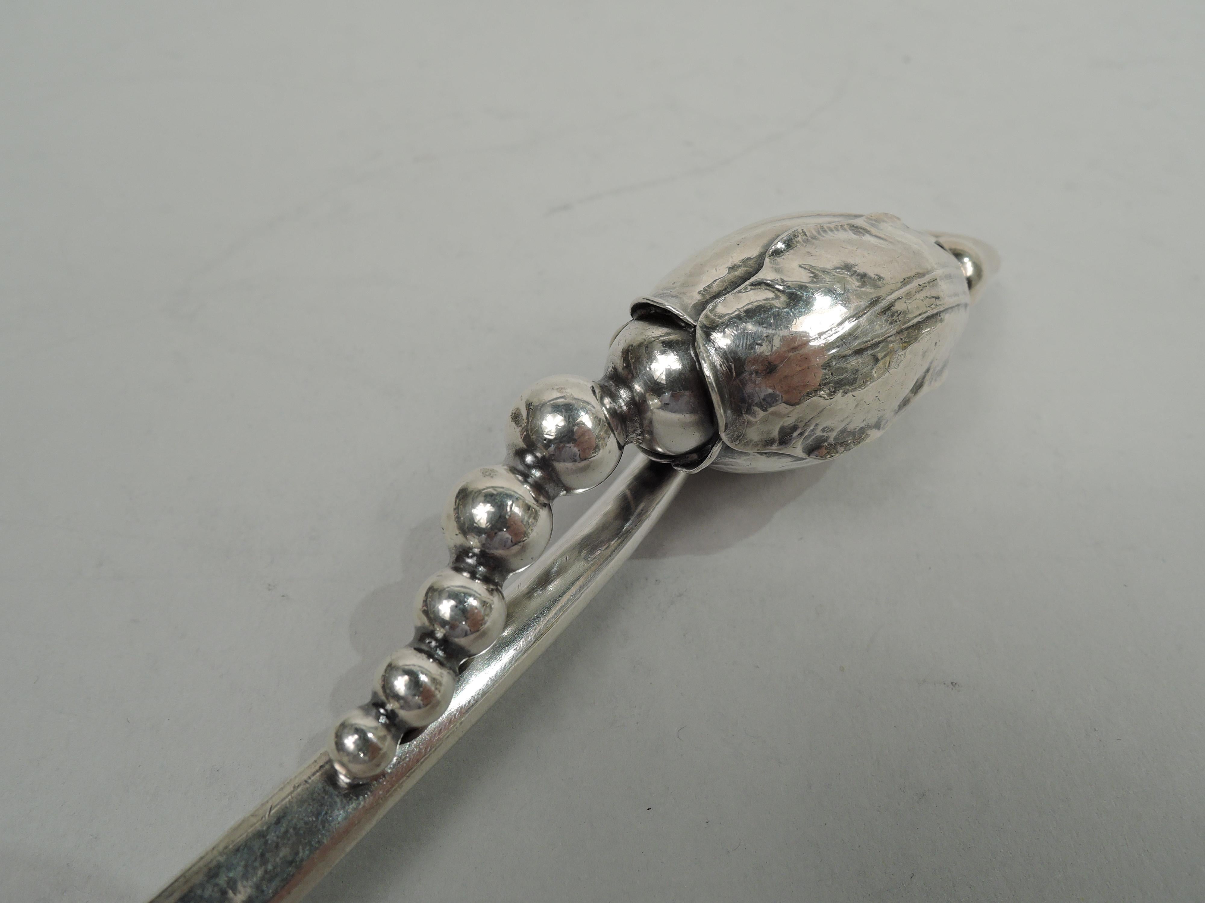 Blossom sterling silver soup ladle. Made by Georg Jensen in Copenhagen. Upward tapering stem with pendant seed-spilling bod. Ovoid bowl with side spouts. A desirable piece in the historic pattern. Visible hand hammering. Marks include maker’s stamp