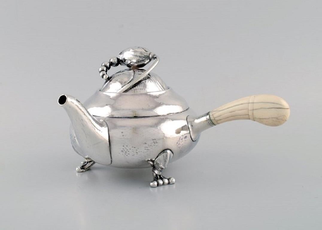 Georg Jensen Blossom teapot in hammered sterling silver with ivory handle. 
Model 2C. Dated 1915-1930.
Measures: 24 x 14 cm (incl. Handle).
In excellent condition. Minimal age-related wear.
Stamped.
Our skilled Georg Jensen silversmith /