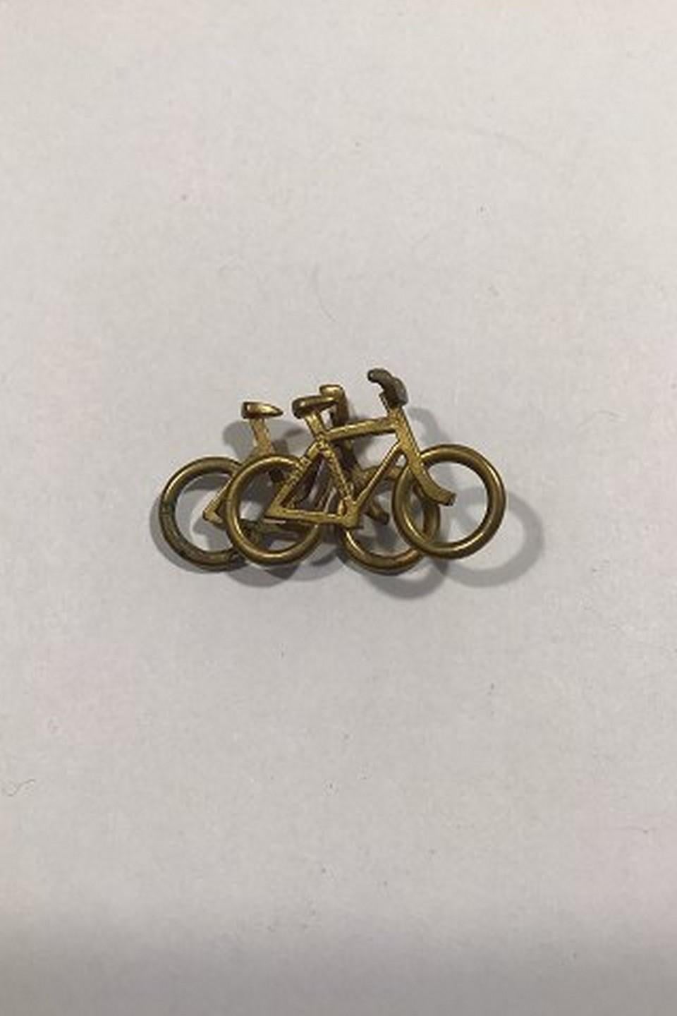 Georg Jensen Brass Double Bicycle Pendant No 5215. 
Design by Ole Bent Petersen 
Measures 3.6 cm x 2 cm(1 27/64 in x 0 25/32 in) 
Weight 4.6 gr/0.16 oz
Item no.: 438462