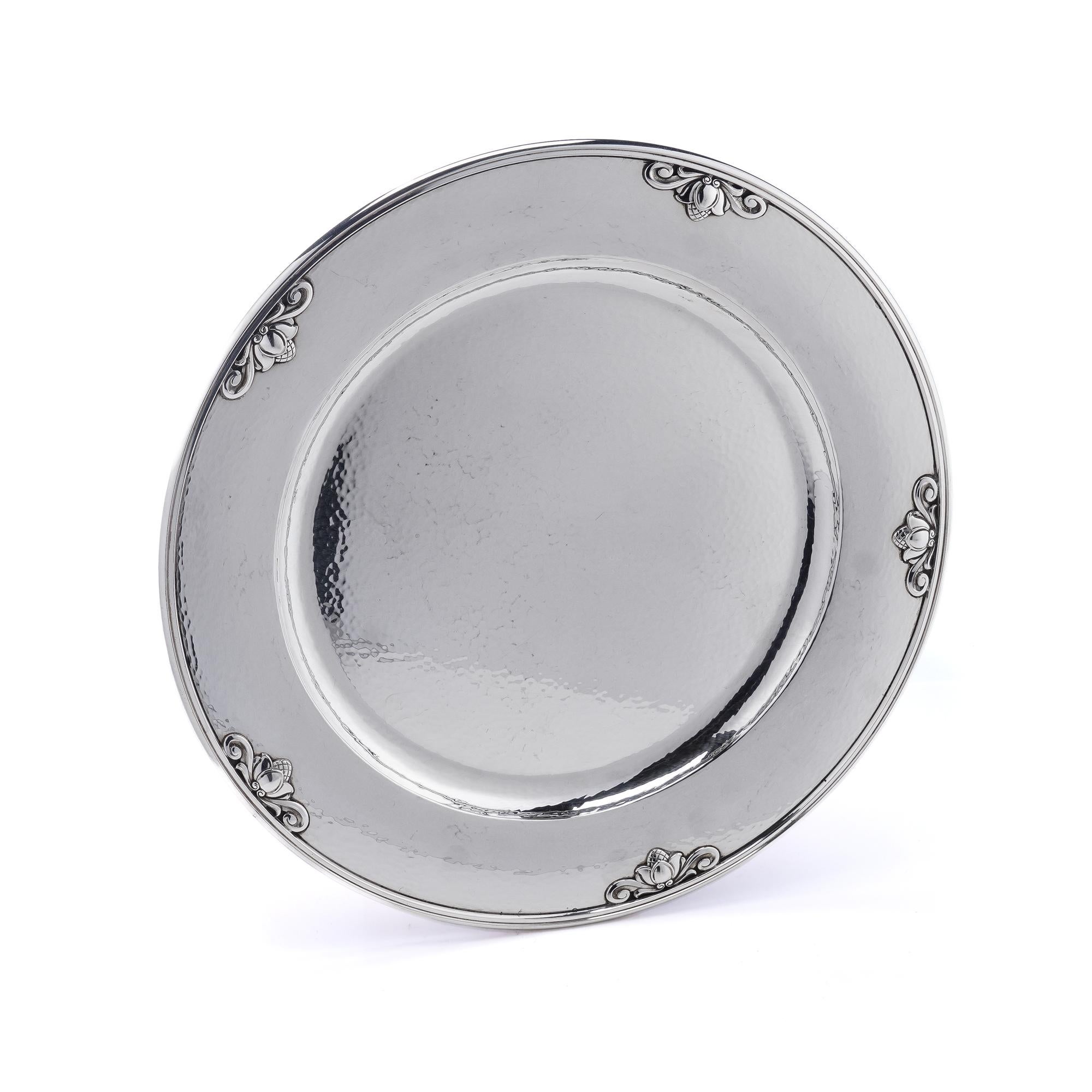 The Georg Jensen vintage sterling silver bread plate with Acorn pattern, designed by Johan Rohde, is a piece of Danish silverware that was produced by the renowned Georg Jensen silver company. The bread plate features a classic design that includes