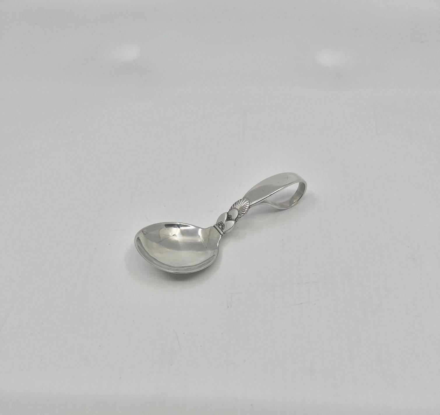 A Georg Jensen sterling silver baby spoon with curved handle, item 095 in the Cactus pattern, design #30 by Gundorph Albertus from 1930.

Additional information:
Material: Sterling silver
Styles: Art Deco
Hallmarks: With Georg Jensen hallmark, made
