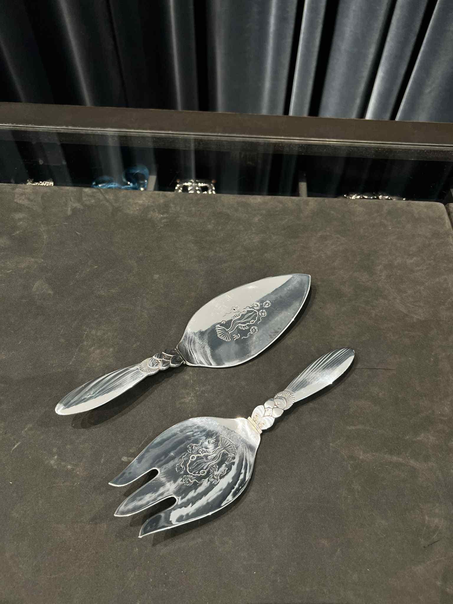 An early Georg Jensen Cactus two-piece sterling silver fish serving set, featuring the distinctive Cactus pattern, design #30 by Gundorph Albertus from 1930. Each piece is adorned with a hand-chased fish motif and intricate hand-cut fish