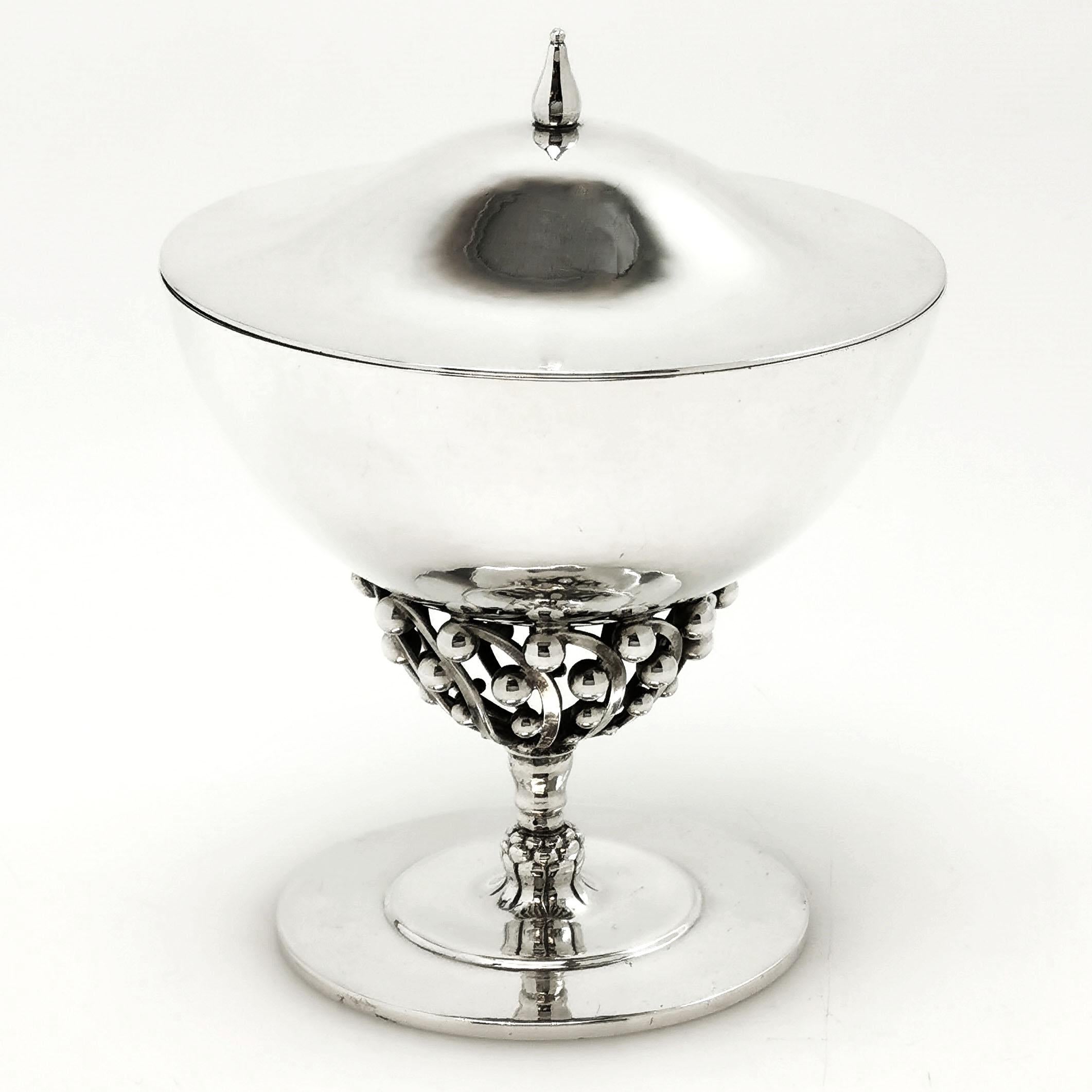 A pretty Georg Jensen Danish Silver lidded Bowl on tall stem with and open scroll and bead design. The Dish has an elegant domed lid with a pointed finial. The Bowl stands on on a flat stepped circular foot.

Made by Georg Jensen in Denmark circa