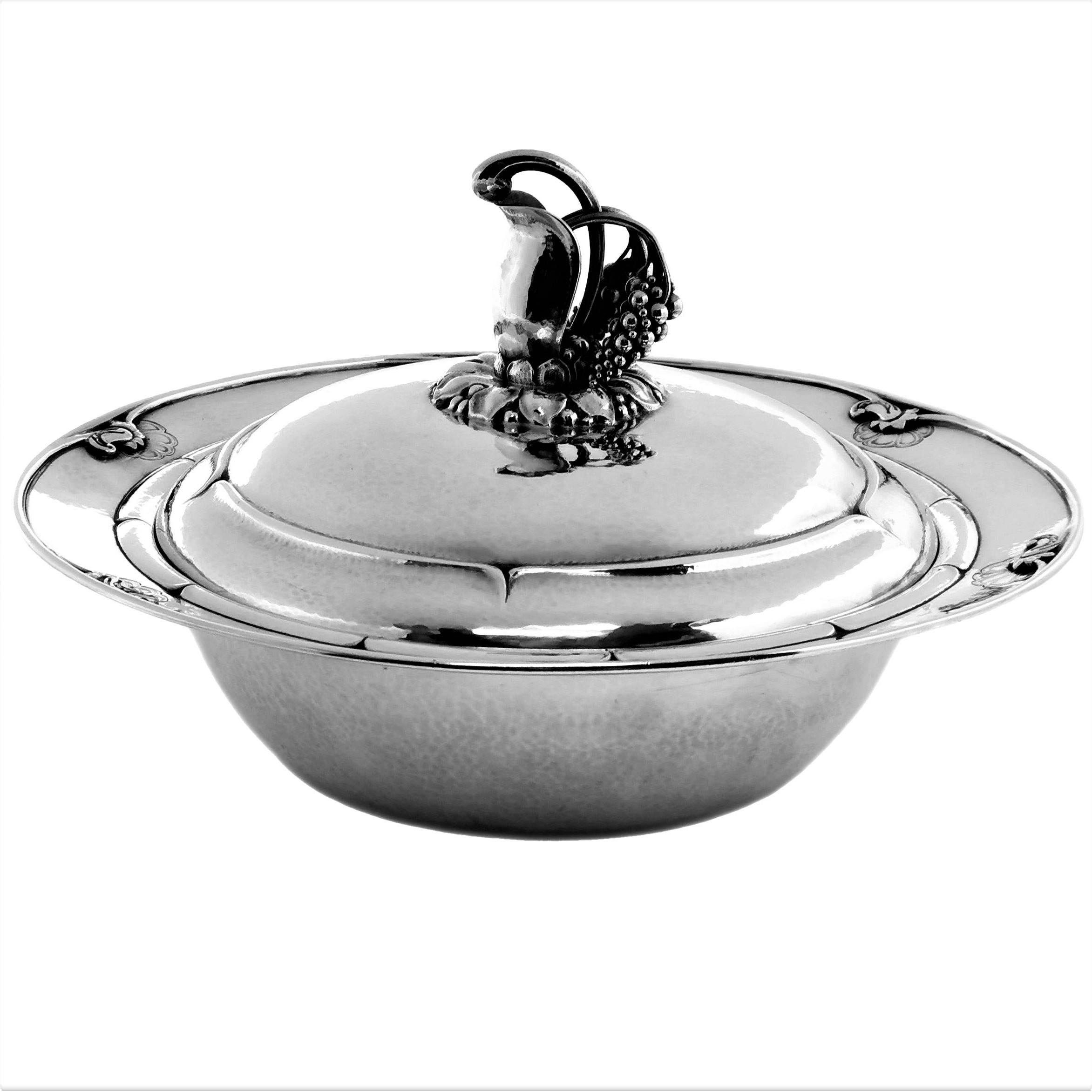 A magnificent Danish Lidded Silver Vegetable Dish with a removable divider insert by Georg Jensen. The Rim of the Tureen has a repeating stylised floral pattern around the rim and the lid is embellished with an impressive finial. The entire dish has