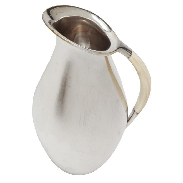 Large silver water pitcher with a flaring lip and a curved bone handle and lightly hammered surface.
Hallmarked for 925 silver/ Georg Jensen mark for post 1945/ 432 F/ DESSIN Johan Rohde/ Denmark/ Sterling.

Exhibited:
The Museum of Modern Art,