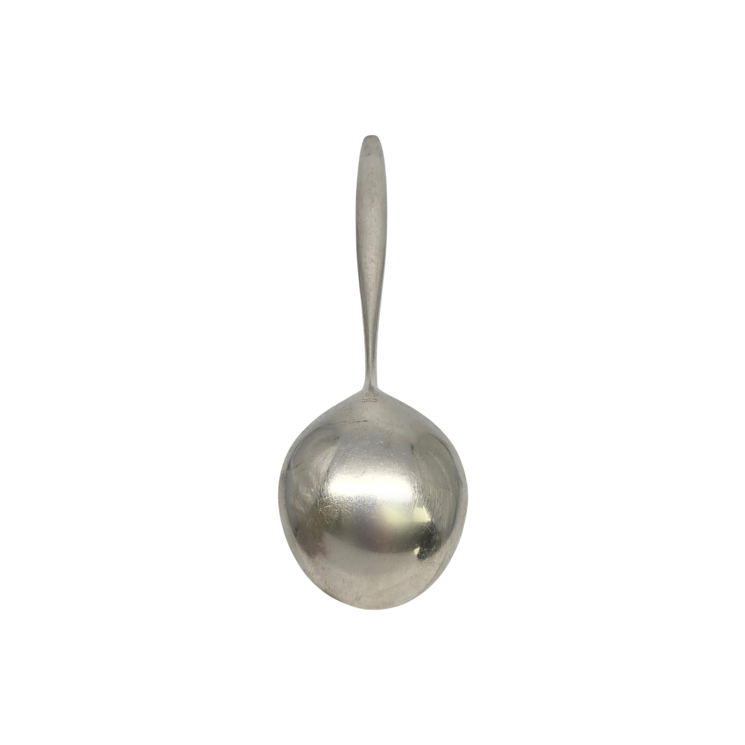 Piccolo cucchiaio da portata in argento sterling di Georg Jensen Denmark con motivo Cypress.

Creato da Tias Eckhoff, vincitore di un concorso di design per commemorare il 50° anniversario di Georg Jensen Silversmith nel 1953. Il modello semplice e