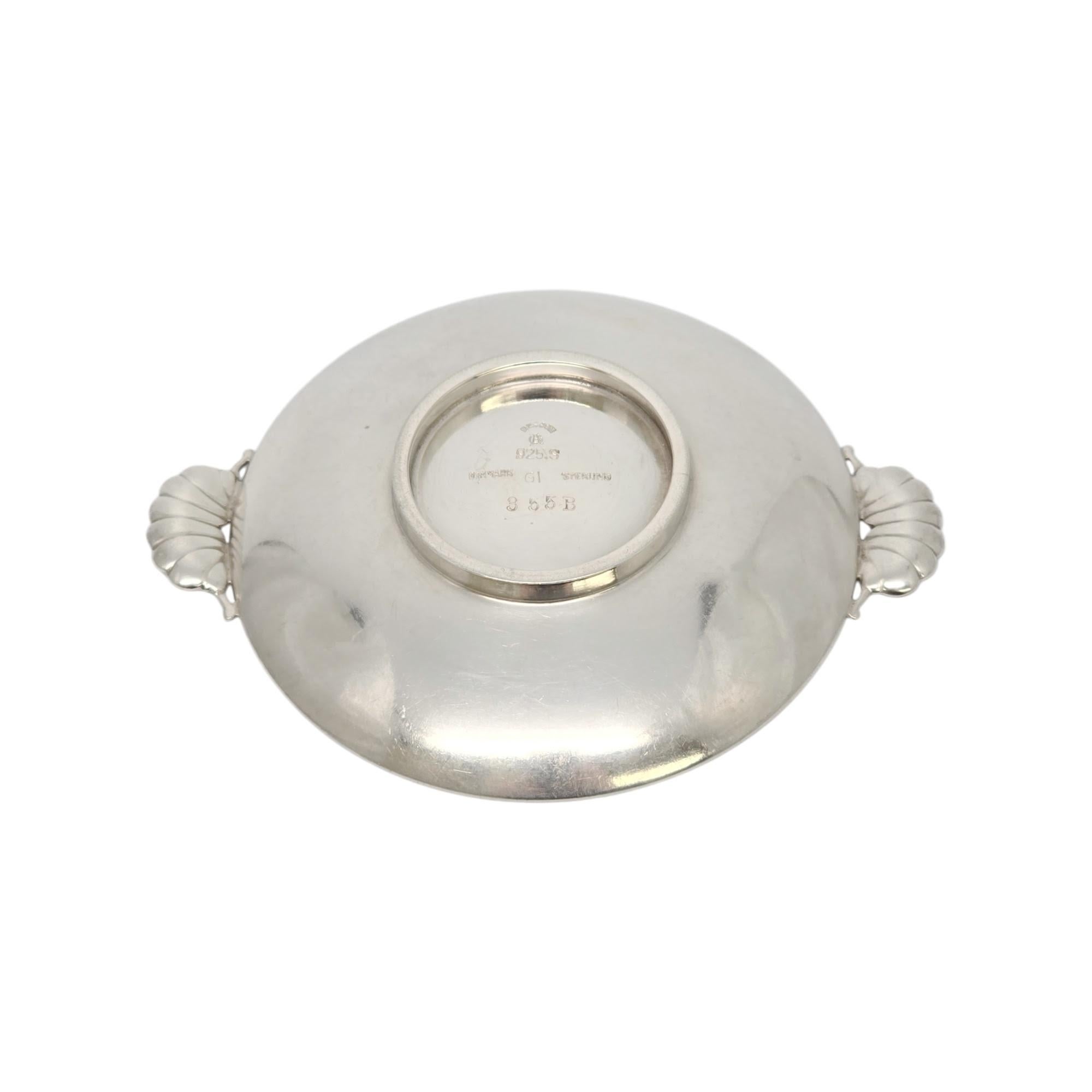 Cantinetta per sale in argento sterling Georg Jensen Denmark, modello #355B.

Disegnata da Gundorph Albertus (1887-1970), questa piccola ciotola rotonda con piedi bassi presenta manici smerlati a forma di fiore. Il marchio GI è stato utilizzato tra