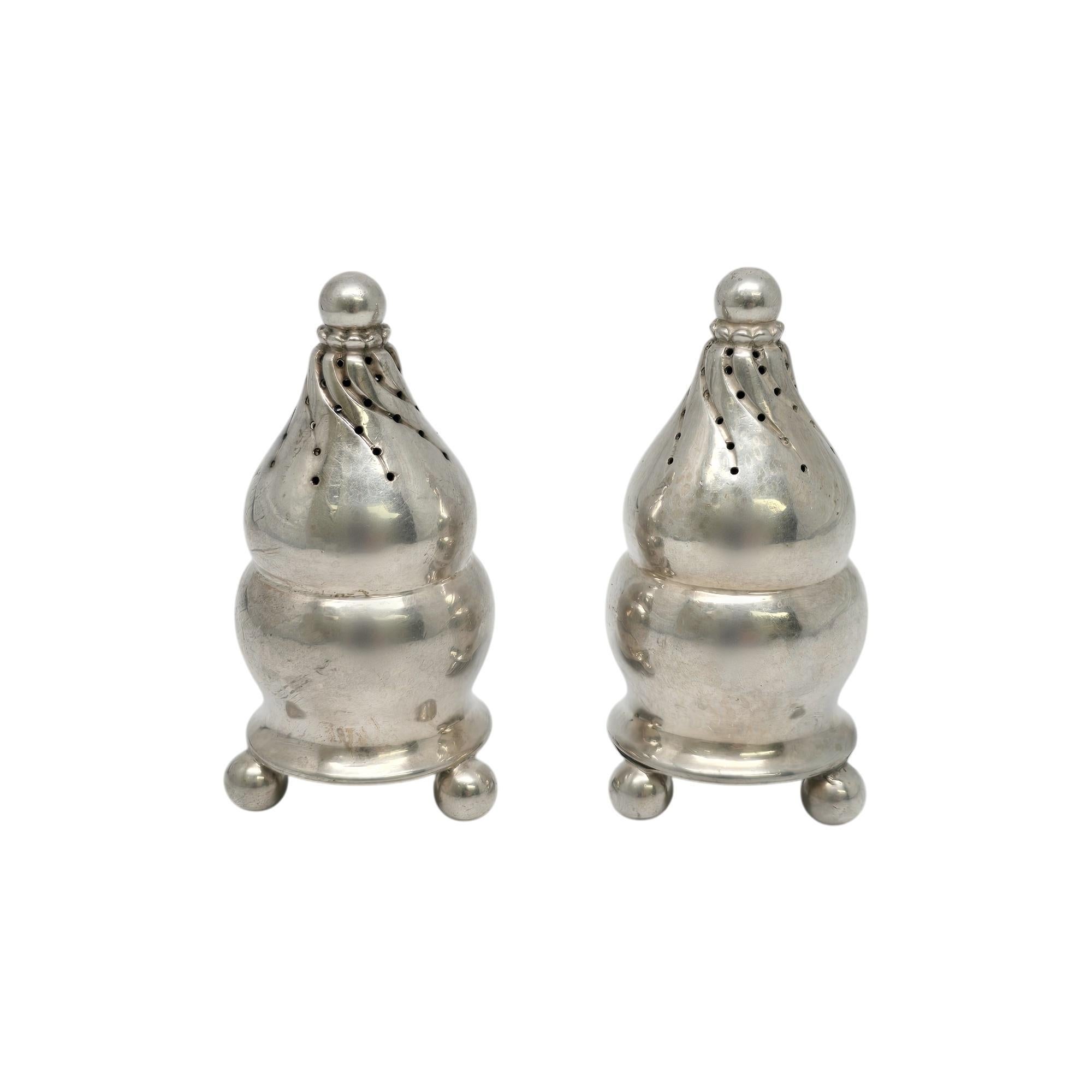 Shakers in argento sterling Georg Jensen Denmark d'epoca con monogramma, modello #410.

Il monogramma sembra essere H. H. sul fondo di ogni shaker.

Questi Shakers hanno una forma a bulbo con 3 piedini a sfera e un design a torsione nella parte