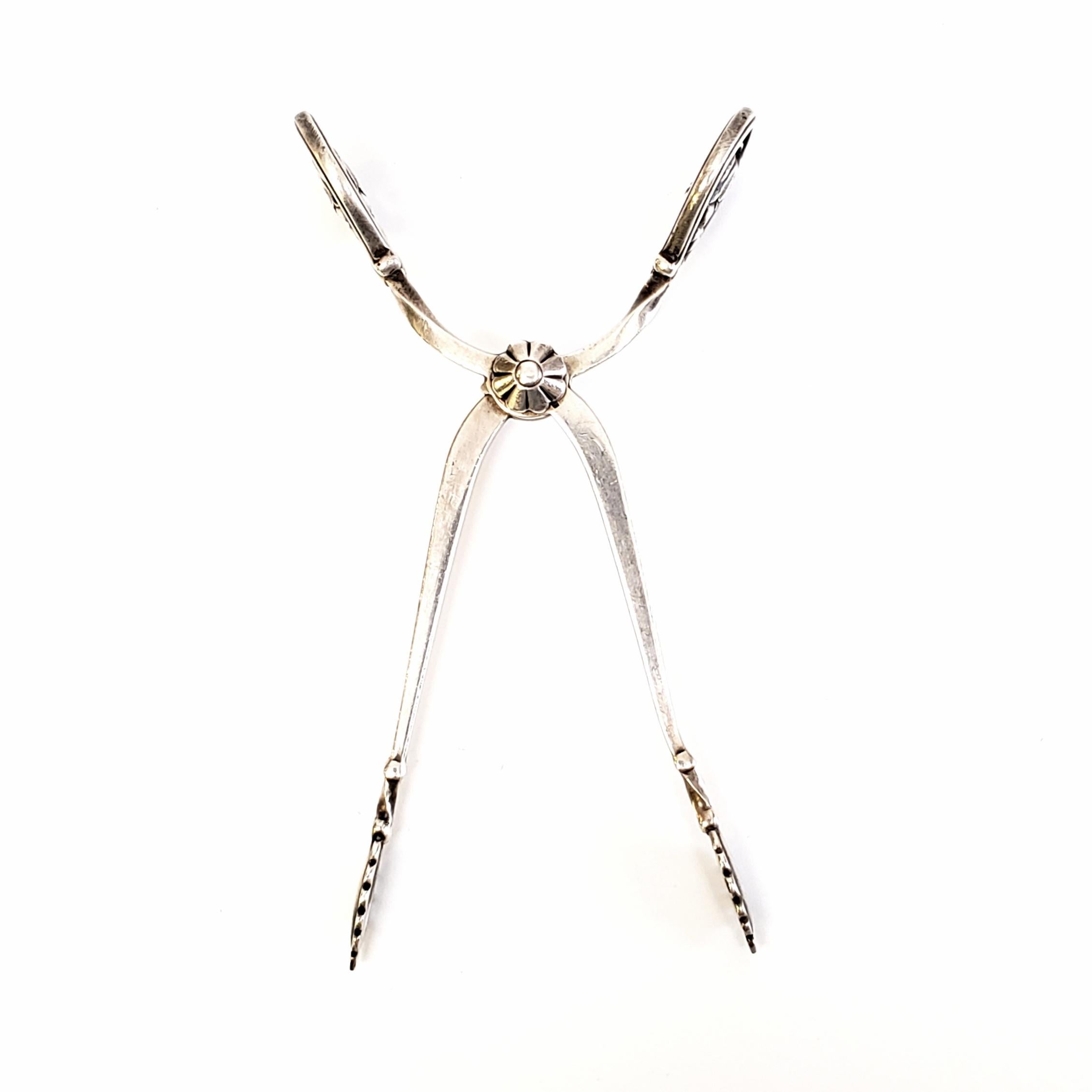 Antique Georg Jensen Denmark sterling silver sugar tongs in the Blossom pattern.

The Blossom pattern was created by Georg Jensen himself for a full cutlery range in 1919. The pattern features a bud on the verge of blossoming, the epitome of