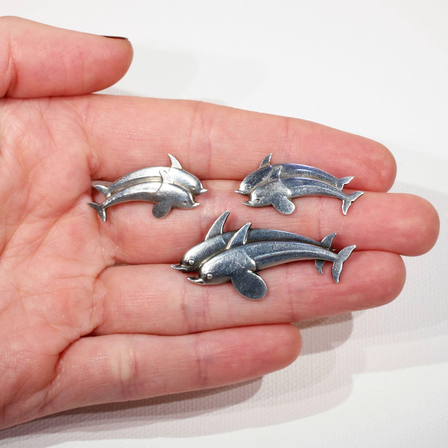 This vintage Georg Jensen dolphin brooch and earring set was handcrafted in Denmark around 1950. This Mid-Century set was made in sterling silver and features an adorable double dolphin motif. All three pieces together weigh 10.8 grams. The brooch