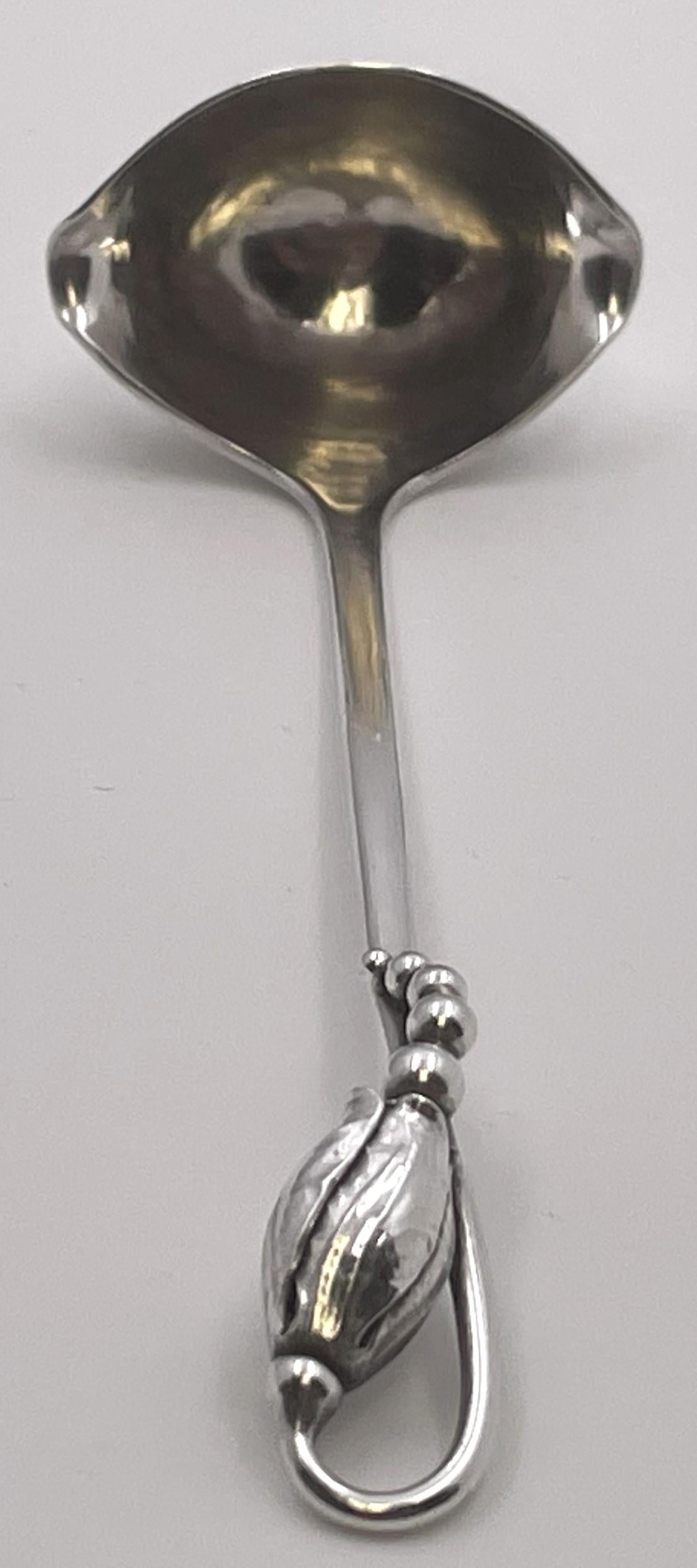 Georg Jensen sterling silver beautifully hand-hammered cream ladle in the celebrated Blossom pattern pattern and in Art Nouveau style, adorned with stylized natural and geometric motifs, from the 1930s or early 1940s. It measures 5'' in length and