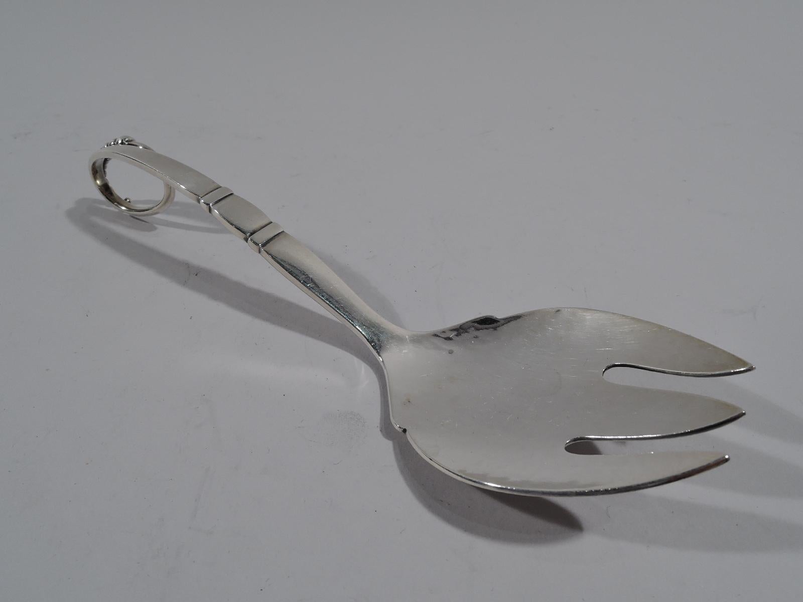 Hand-hammered sterling silver serving fork in pattern no. 41. Made by Georg Jensen in Copenhagen, circa 1930. Curved shank with 3 tines. Tapering handle with 2 bands and loop terminal with graduated beading. Marked “41/ Sterling / Denmark / Georg