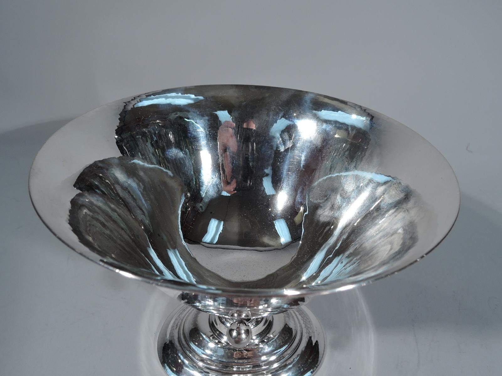 Hand-hammered sterling silver footed bowl. Made by Georg Jensen in Copenhagen. Round bowl with flared rim on open support on stepped oval foot. Support comprises tendril terminating in bead and mounted to leaf alternating with notched tendril. An