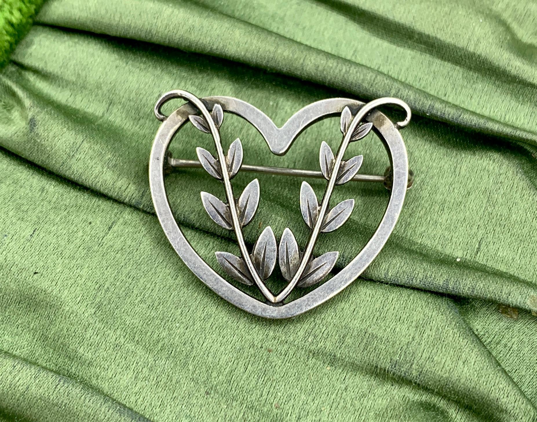 This is the wonderful Georg Jensen Denmark Sterling Silver Heart and Leaf Brooch.  The brooch is fully hallmarked with the Georg Jensen oval dotted punch, Sterling Denmark and design number 242B.  The classic brooch with open work design and the