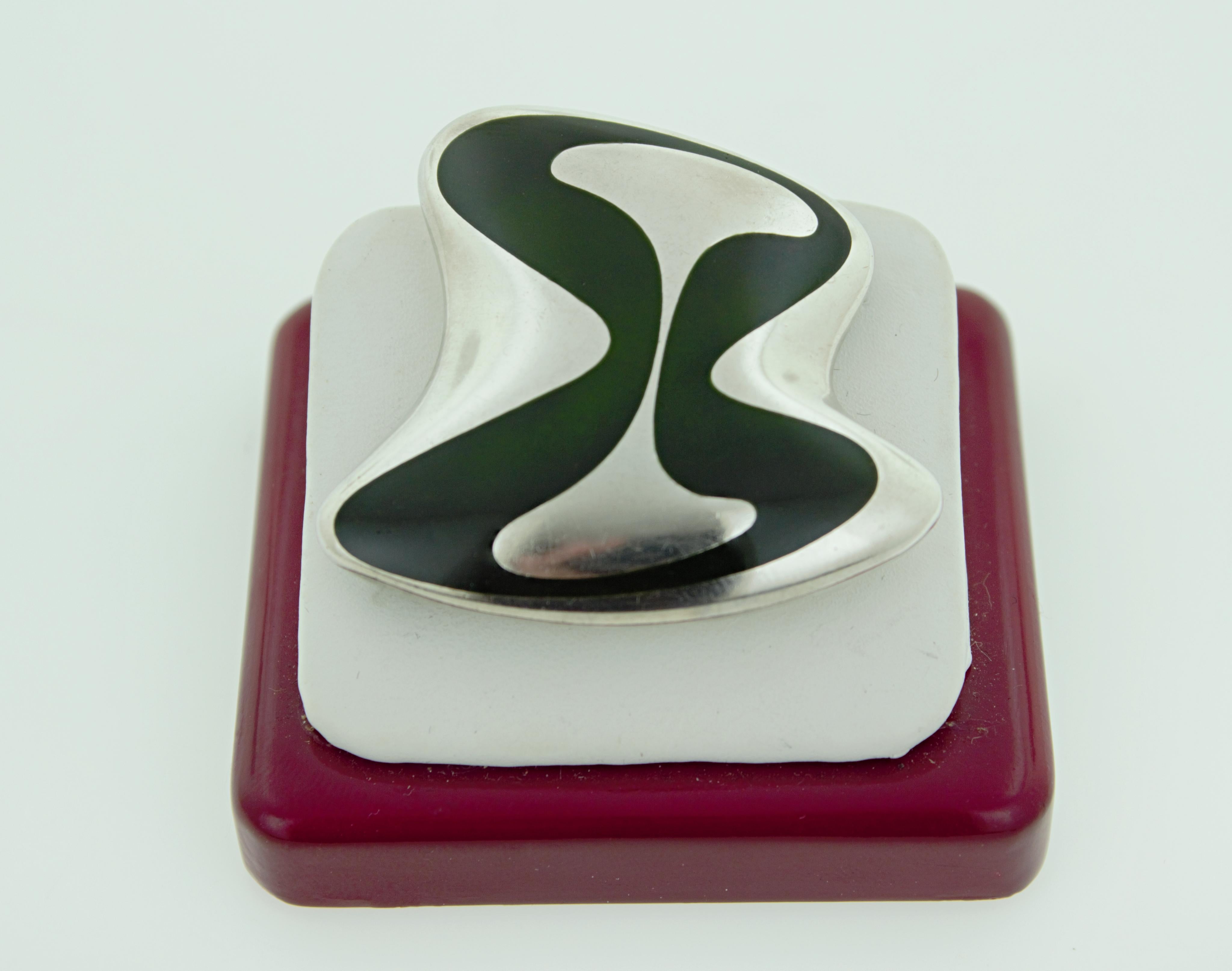 Mit dunkelgrüner Emaille, in Sterling Silber modern amorph hoch
polierte Brosche, 45 x 26,7 x 9,5 mm, eingekreistes Zeichen HK, Georg Jensen,
Sterling Dänemark, 315, Bruttogewicht 17,48 Gramm.
CIRCA: 1954
Henning Koppel entwarf von 1946 bis 1981 für