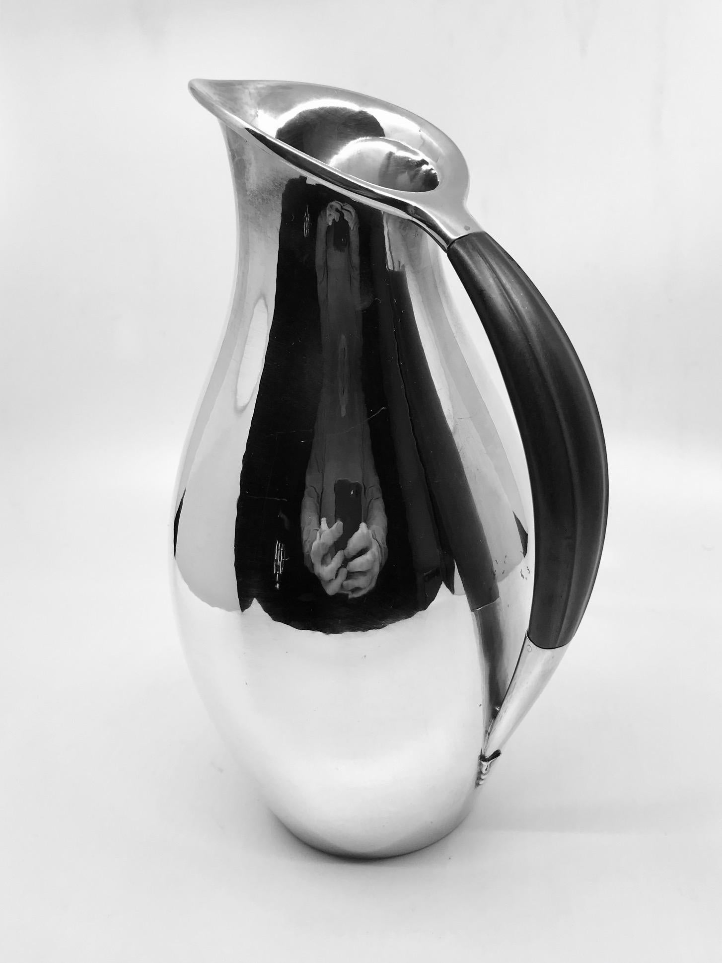This is a Georg Jensen sterling silver pitcher with ebony handle, design #432E by Johan Rohde from 1920.
This design by Rohde was the topic of many conversations between him and Georg Jensen Silversmithy, as its minimalistic look in 1920 was before