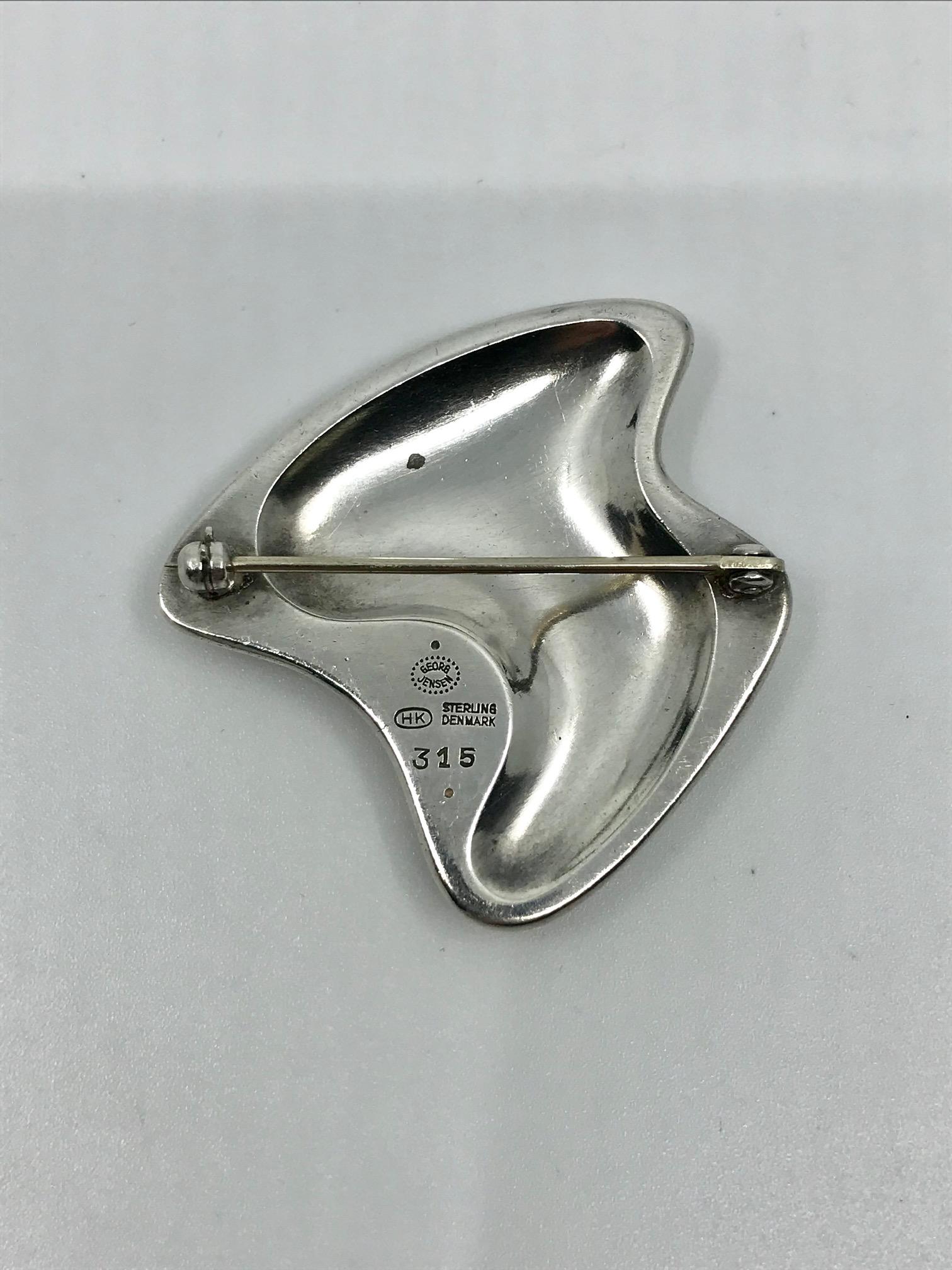 Modern sterling silver Georg Jensen brooch with green enamel, design #315 by Henning Koppel from circa 1954.
Measures 1 3/4″ x 1 3/4″ (4.3cm x 4.3cm).
Post 1944 Georg Jensen hallmark.
The enamel is undamaged.