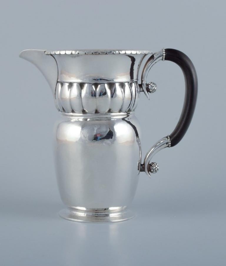 Georg Jensen, large Art Nouveau pitcher in sterling silver. 
Early and rare model. Hammered finish. Ebony handle.
Approximately from 1918.
Model number: 49.
Stamped.
With French import marks.
Perfect condition.
Dimensions: H 17.7 cm x D 18.5 cm