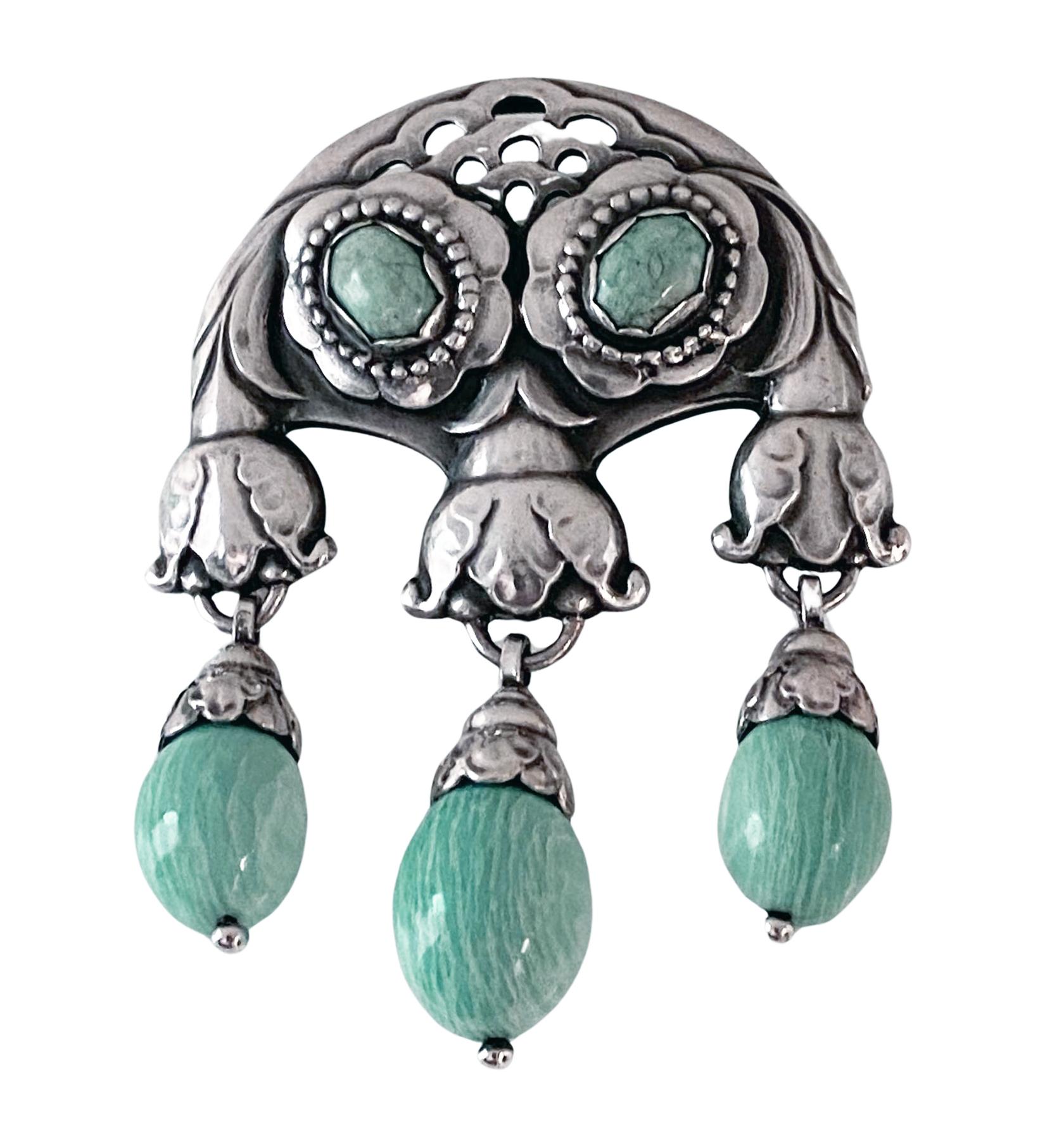 Georg Jensen large rare design Silver Amazonite Master Brooch, C.1933. Designed as foliate motifs set with 2 oval amazonite and suspending three amazonite acorn shaped drops. Measures: 9.00 x 6.50 cm, 1933-44 marks GJ in box 925 Sterling Denmark