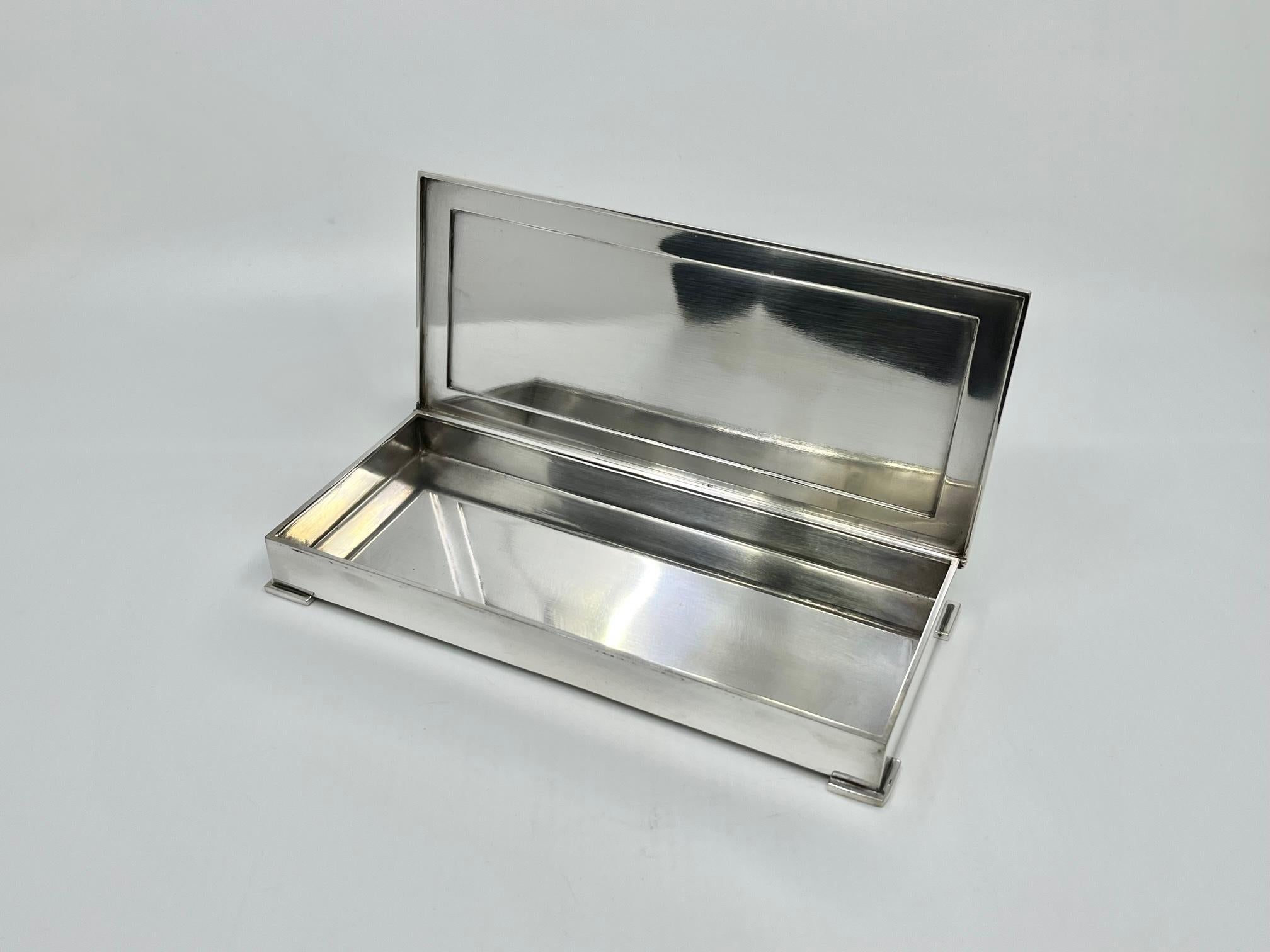 A large early sterling silver Georg Jensen Art Deco box, design #827 by Harald Nielsen from circa 1938. A heavy rectangular box supported by four art deco L shaped feet.  The lid with a raised squared lid centered. This box exceeds the standard high