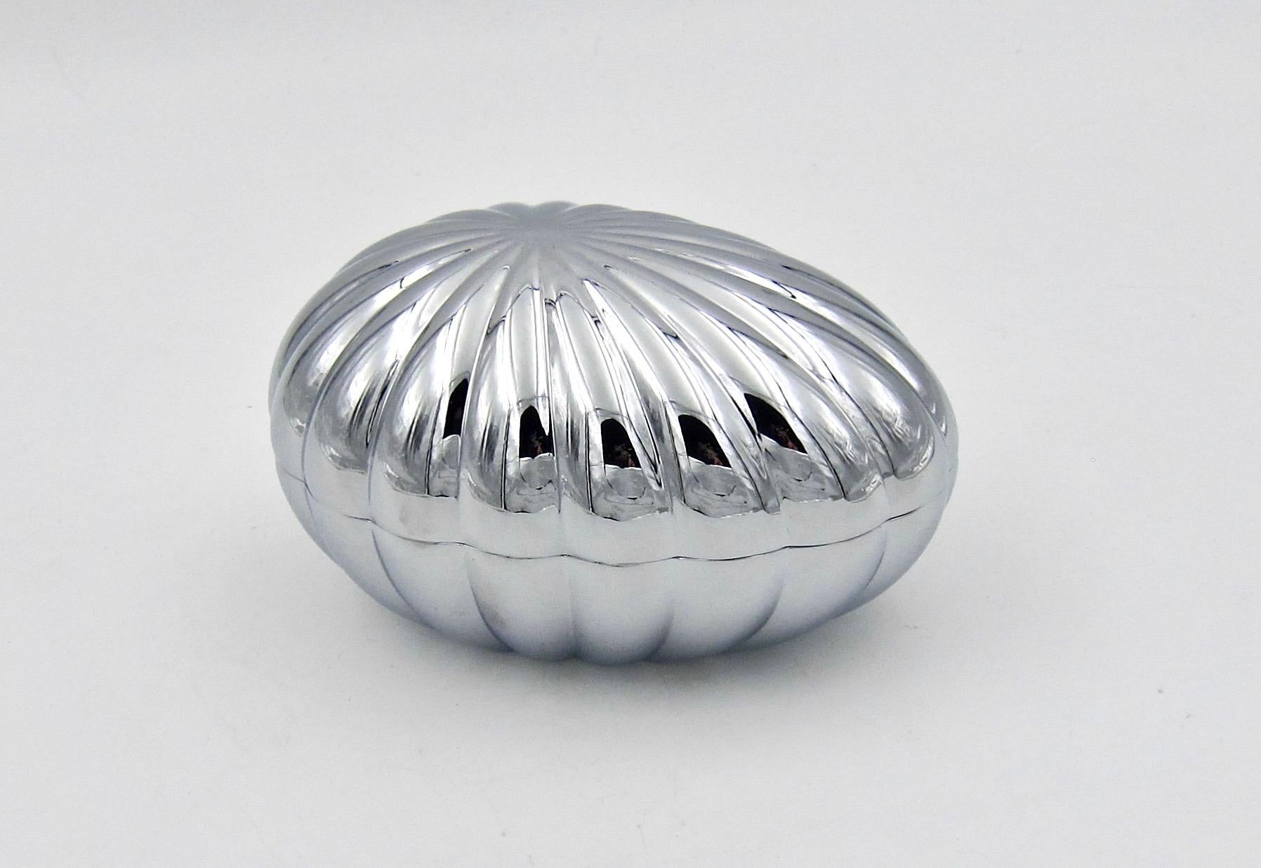 A scalloped and highly polished chromium-plated bonbonniere box shaped like an egg, designed by Philip Bro Ludvigsen for Georg Jensen. The sculptural bonbonniere was designed to hold candies but is an ideal size and shape for jewelry, keys, and