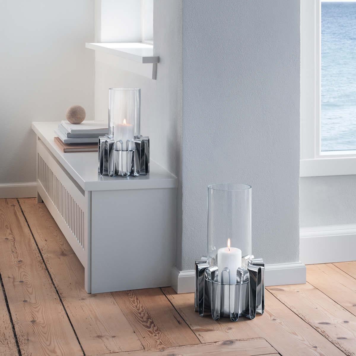 Bring a sense of the drama of the ocean to your terrace or garden with the Frequency hurricane lantern. Inspired by the movement of waves and the way they capture light, the lantern beautifully encases a glass column shade in a circle of stainless