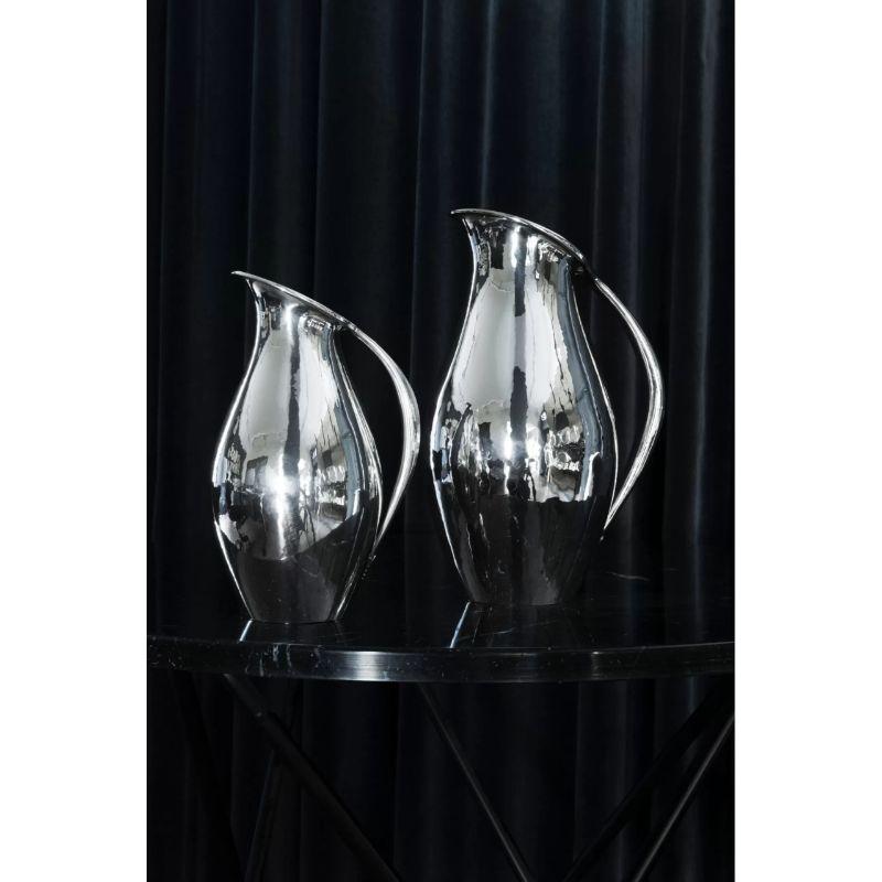 A pair of iconic Georg Jensen sterling silver pitchers, design #432 envisioned by the renowned artist Johan Rohde in 1920.  Known for its timeless elegance and innovative minimalistic look, this iconic pitcher remains a testament to the visionary by