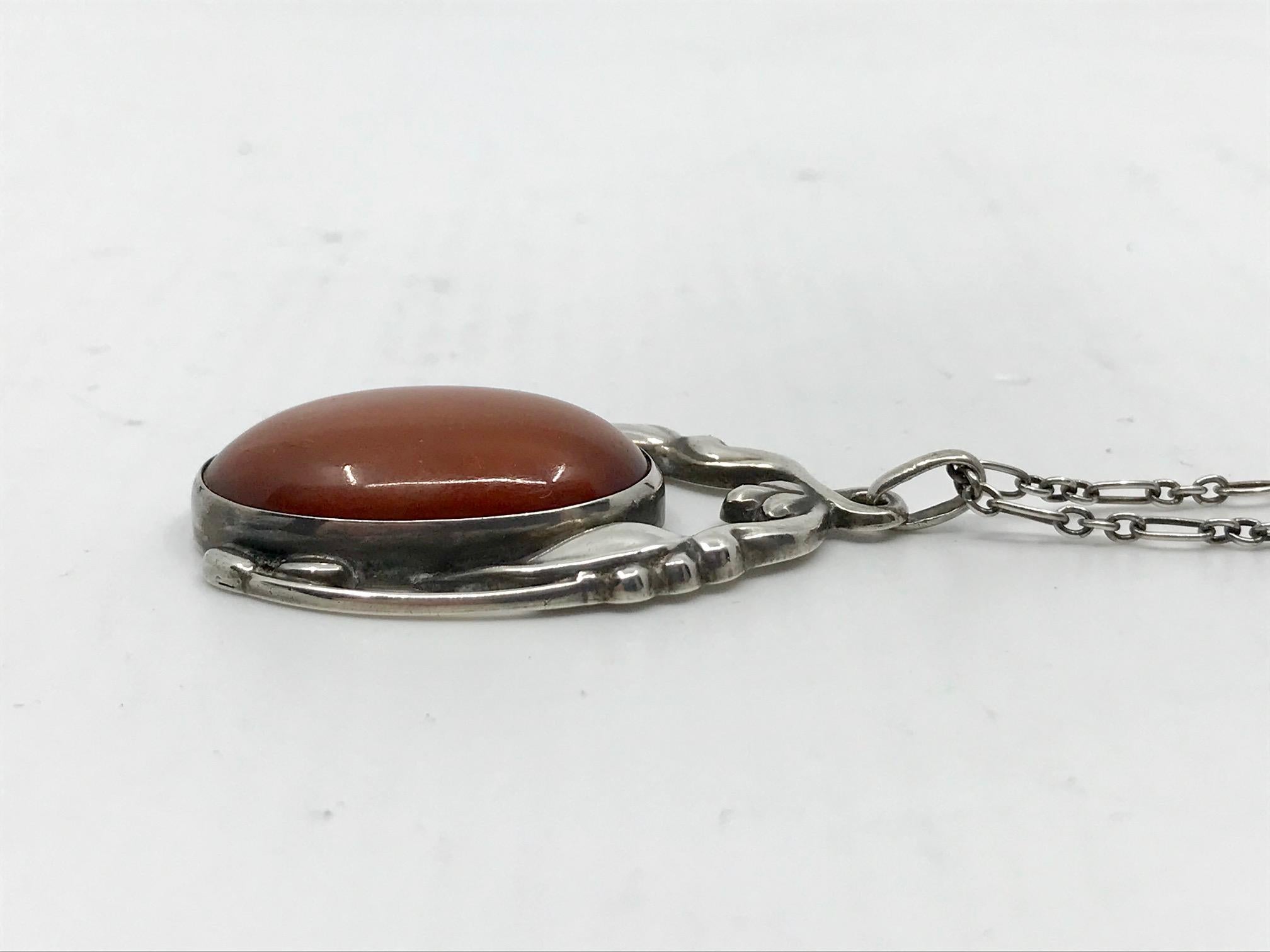 Vintage silver Georg Jensen pendant with a large oval cabochon set amber stone, design #49 by Georg Jensen from circa 1914.
The pendant measures 2″ x 1 1/4″ and comes on a 23½” chain (5cm x 3.2cm, 60cm).
Vintage Georg Jensen hallmarks from