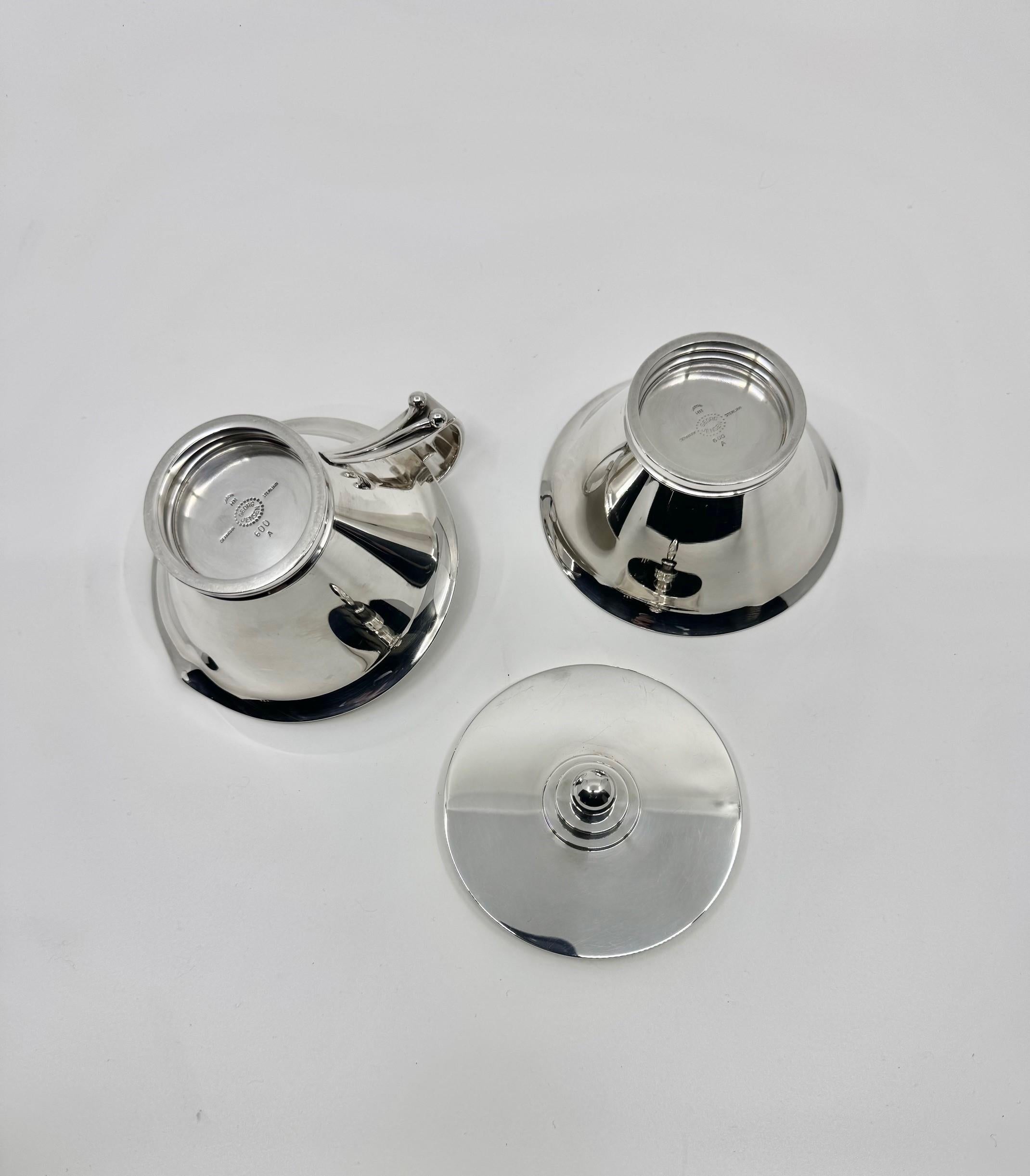 A vintage two-piece sterling silver creamer and sugar set from Georg Jensen, featuring the Pyramid pattern, design #600A by Harald Nielsen from 1930. The Art Deco-inspired design showcases a conical-shaped creamer with a round base and a beveled