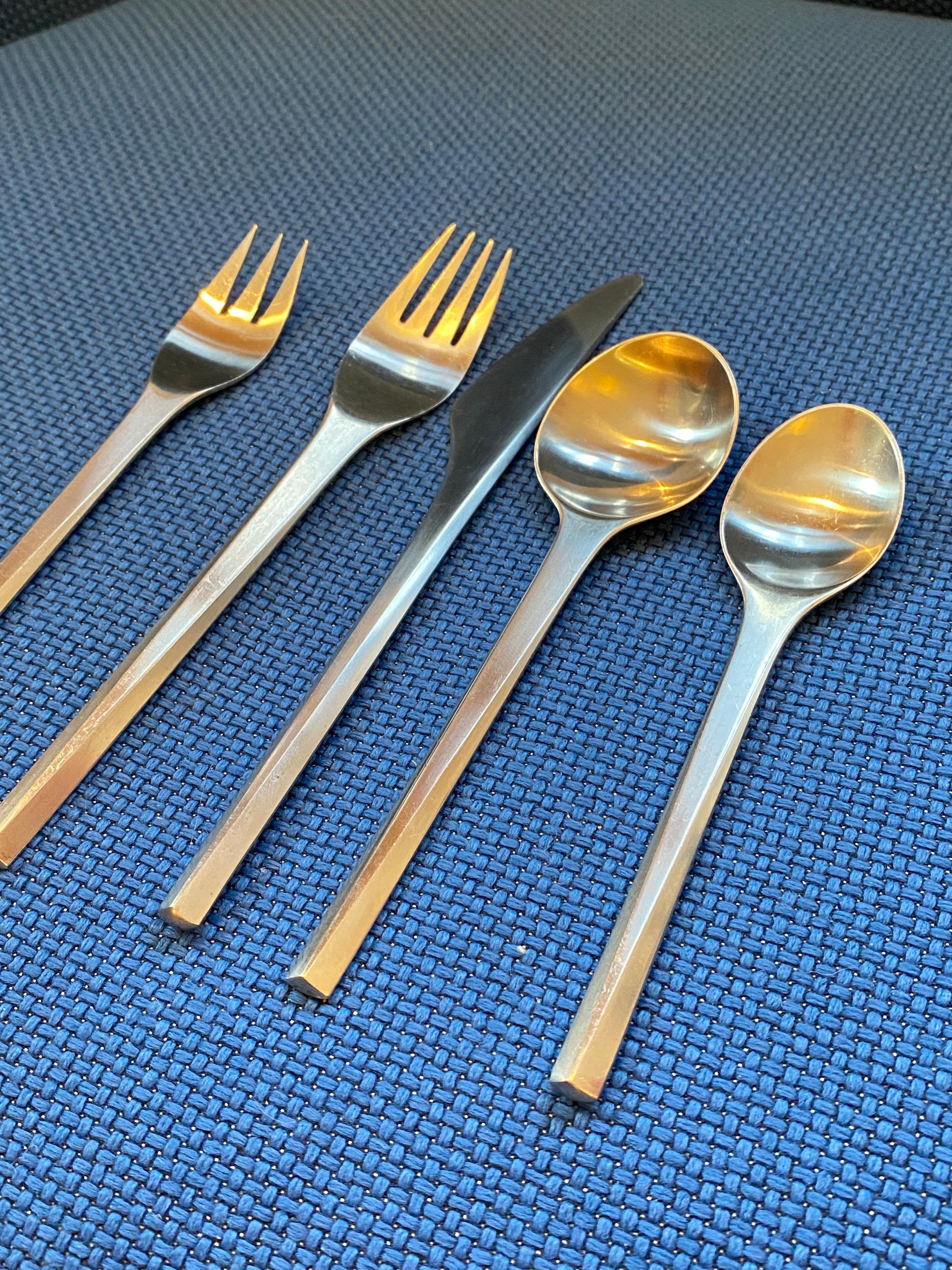 Georg Jensen satin stainless set in the prism pattern, circa 1962 design. Set includes 5 pieces per place setting plus an additional 6 pieces, serving spoons, forks and butter spreaders. Great elegant design with a triangular shape to handles.