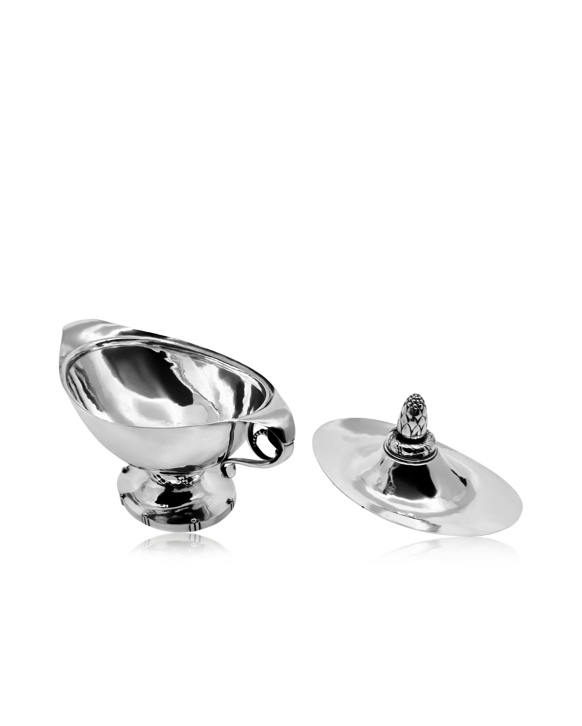 An exceptional and early  Georg Jensen 830 silver bonbonniere, design #170 by Georg Jensen in 1916. The vessel, crafted in an oval shape, features meticulous hand hammering, and is adorned with a gracefully curved lid topped with an acorn finial.