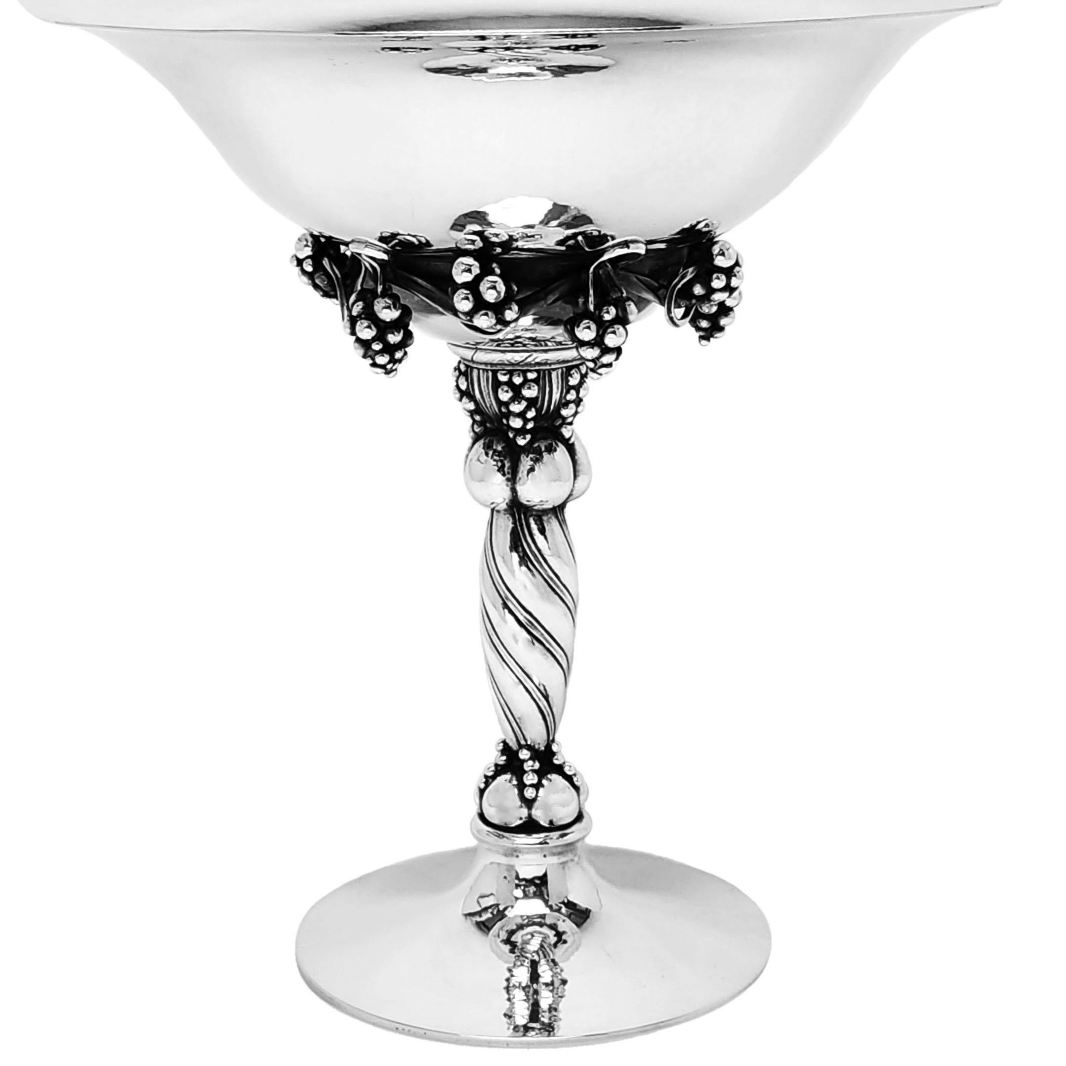Ein prächtiges Silberkompott von Georg Jensen mit dem Muster Nr. 264 A, das ein elegantes Traubenmuster unter einer fein gehämmerten Schale zeigt. Die Silberschale steht auf einem gedrehten Stiel mit einem gehämmerten Spreizfuß.
 
Hergestellt in