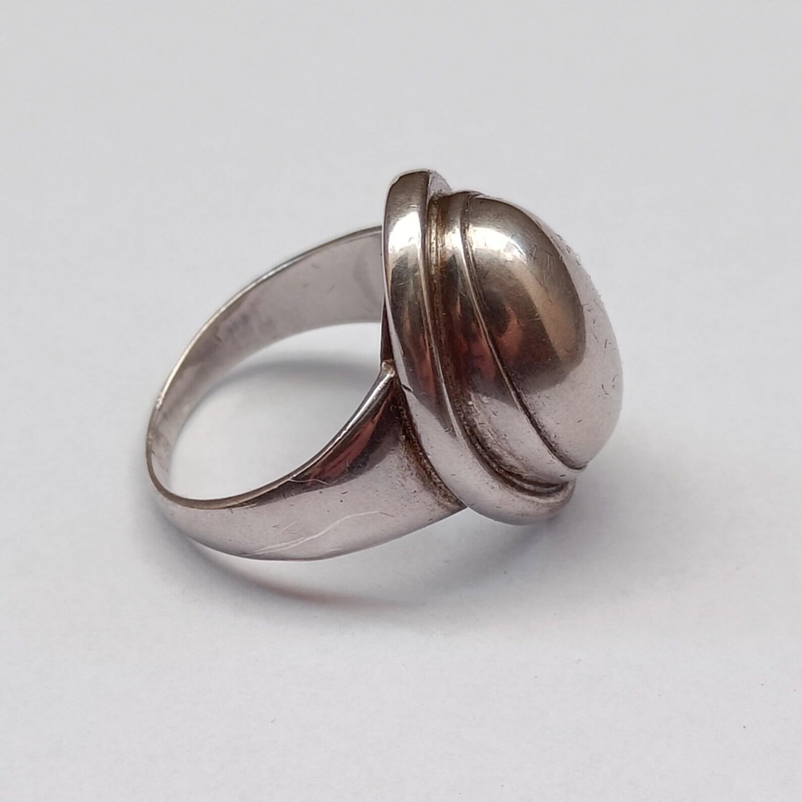 Iconic silver ring, model 46A, designed by Harald Nielsen for Georg Jensen.
Styled in the Jensen brand's signature (squared GJ), it can be dated between 1933 - 1944 (Rare!).

Old ring, not in perfect condition. Some wear on the dome. See