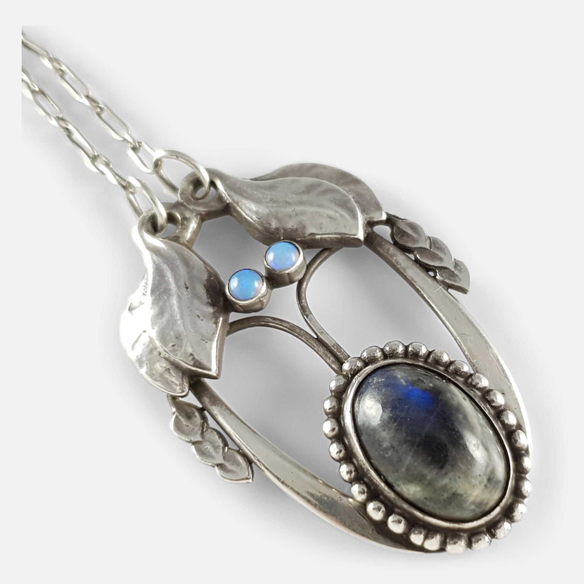 Un ciondolo in argento Georg Jensen, #4, risalente al 1904-1908 circa, con disegni fogliacei incastonati con un cabochon ovale di labradorite all'interno di un bordo di perline e due cabochon di opale, attaccato a una catena d'argento con chiusura a