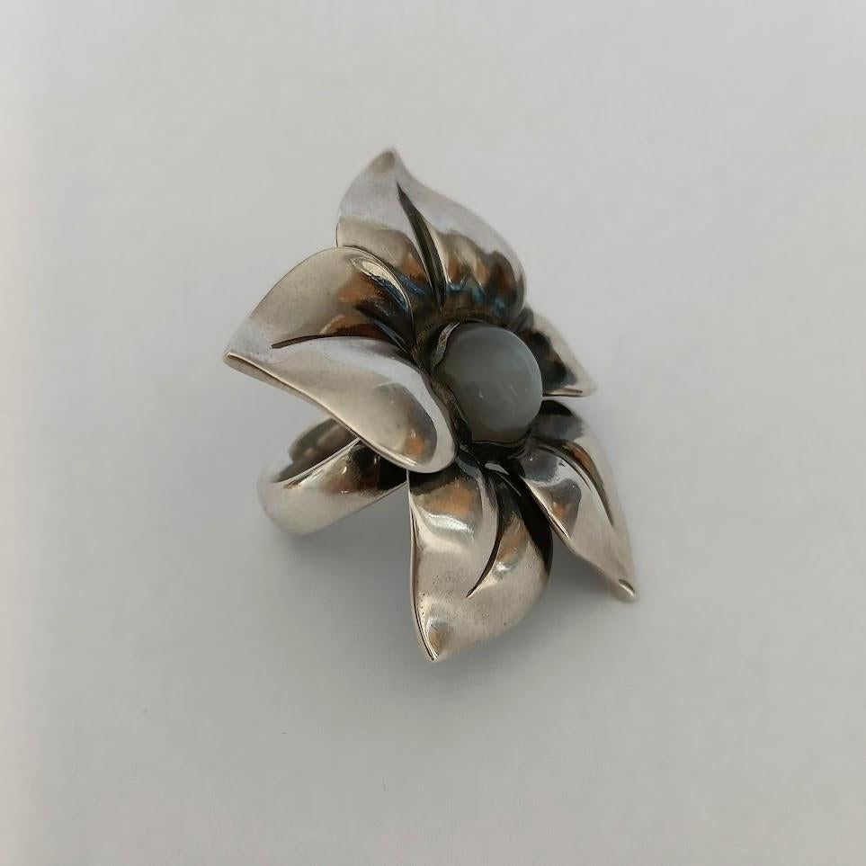 A large floral statement silver ring with grey moonstone cabochon by Georg Jensen
Designed by Regitze Overgaard
Case included
Like new condition

Stamps:
Georg Jensen (dotted, post 1945)
925 S
562 B
50

Size 50, US 5, UK K
Weight 19.8 g

Regitze