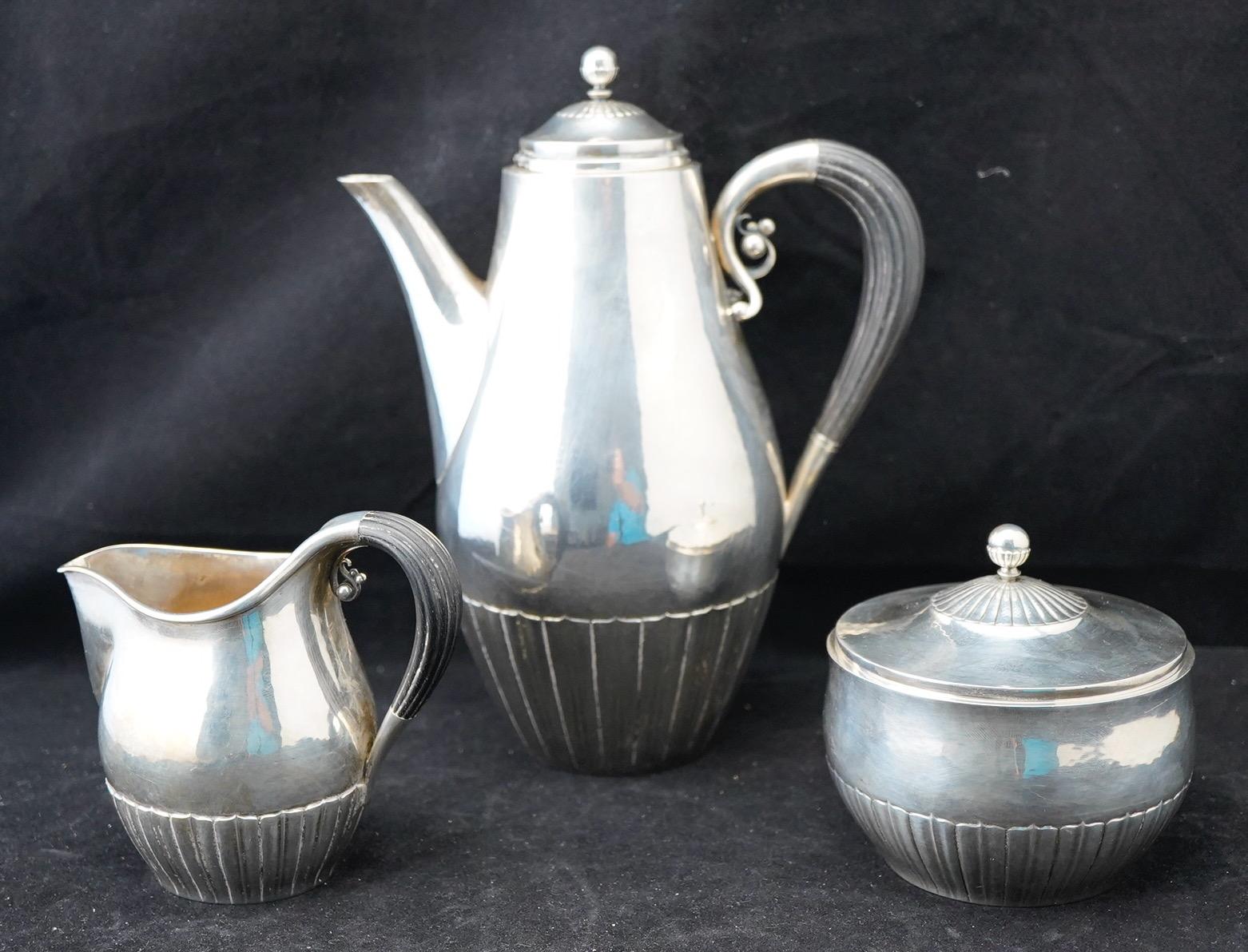 Georg Jensen sterling tea/coffee 3 piece set. Cosmos pattern designed by Johan Rhode for Jensen. Ebony wood handles.
Marked for maker, designer and sterling, after 1945. Pattern number 45C. Coffeepot is 9,25