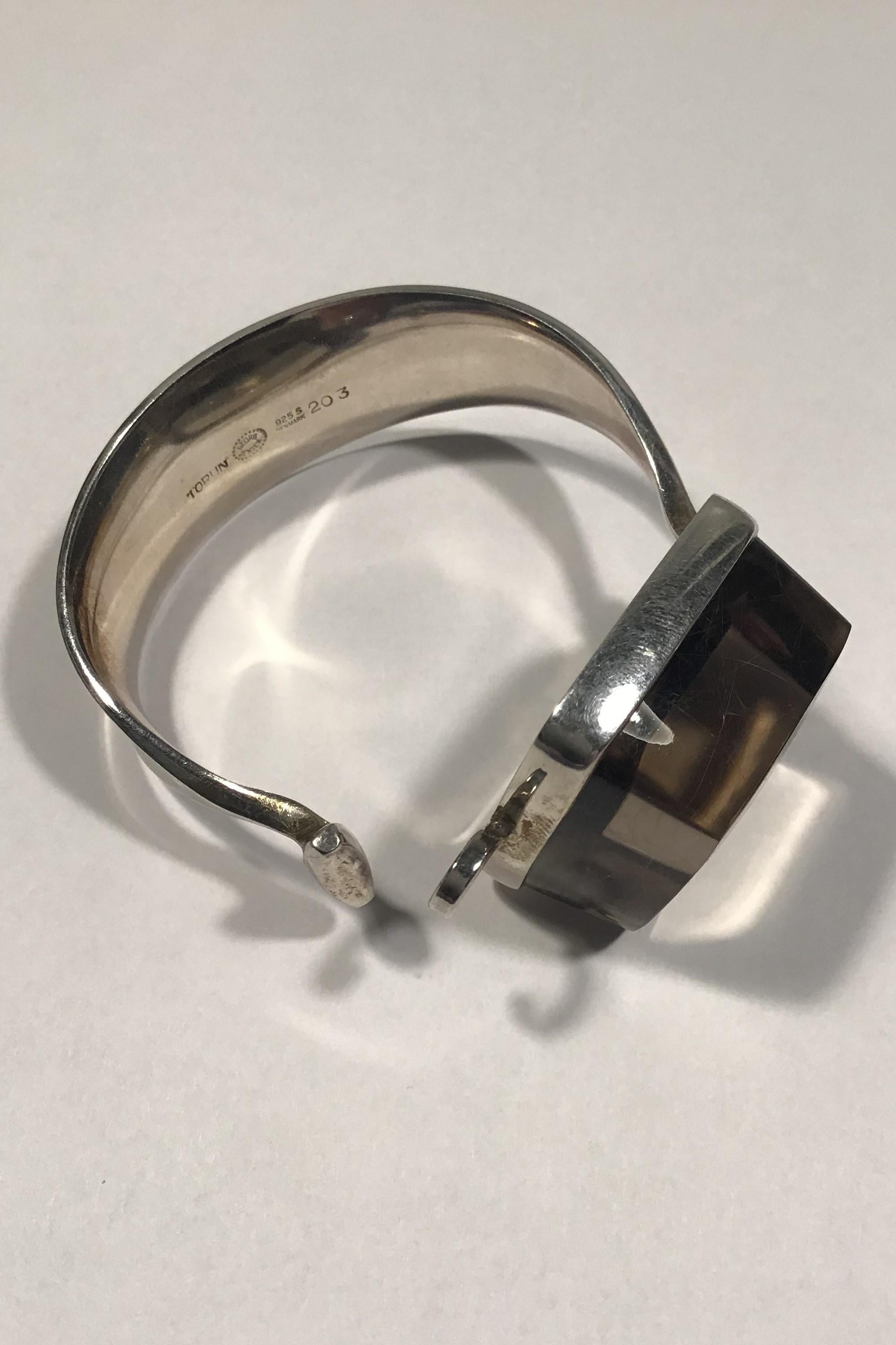 Georg Jensen Sterling Silver Smoke-coloured Rutile Quartz Arm Ring No 203 Torun

Arm ring inside diam5.8 cm(2 9/32 in) 
Stone 3.2 cm x 3.2 cm(1 17/64 in x 1 17/64 in)
Weight 87.9 gr/3.10 oz