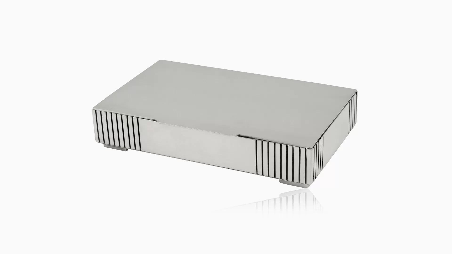 A sterling silver Art Deco Georg Jensen box, design #857 by Jorgen Jensen dating back to 1930. This rectangular box boasts a hinged lid for convenient access. Each corner of the box is adorned with a series of hand-chased lines, elegantly oxidized