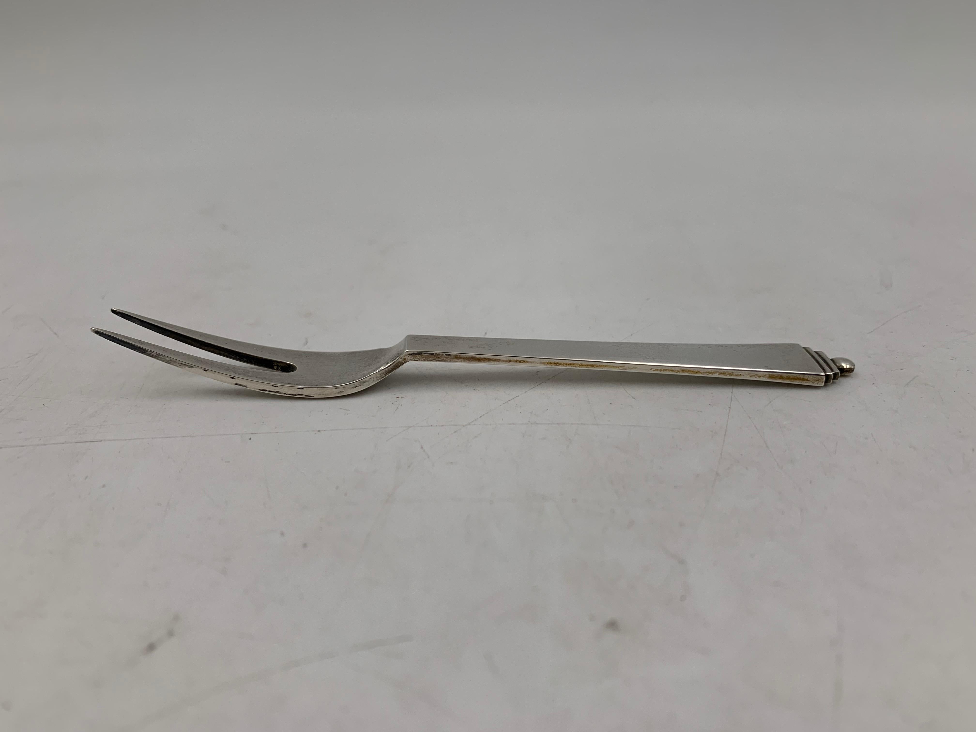 Georg Jensen sterling silver bar lemon fork in renowned Pyramid pattern. It measures 4 1/2'' in length by 1/3'' in width at the widest point and bears hallmarks as shown. 

Georg Jensen, a Danish silversmith, set up his own silver business in 1904