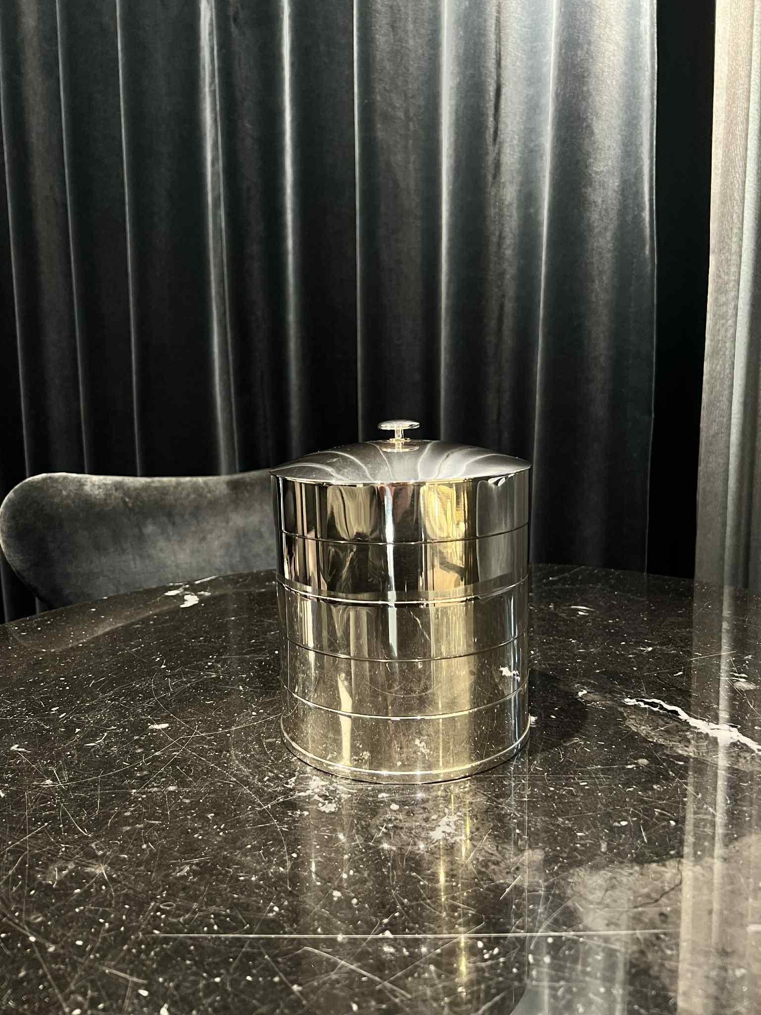 A vintage sterling silver Georg Jensen Art Deco ice pail, crafted by Jorgen Jensen in 1935. Its cylindrical body features four oxidized lines, complemented by a domed top adorned with an elegant Art Deco handle. Originally designed for ice, it now