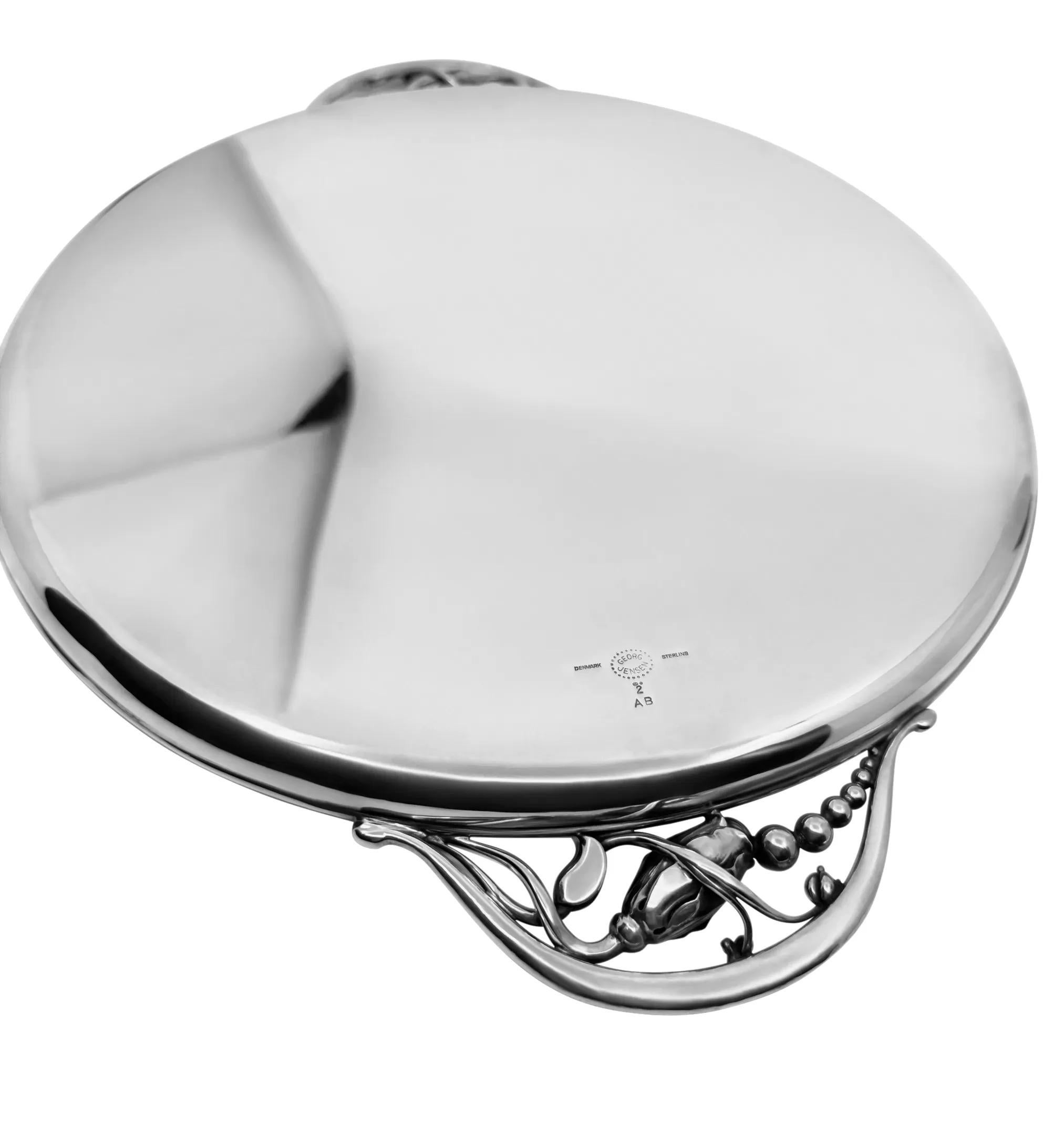 Bandeja circular Georg Jensen Blossom de plata de ley, diseño nº 2AB, de Georg Jensen. El patrón Blossom, introducido por primera vez en 1905 con la célebre tetera, se amplió posteriormente para incluir muchas piezas exquisitas, como esta bandeja.