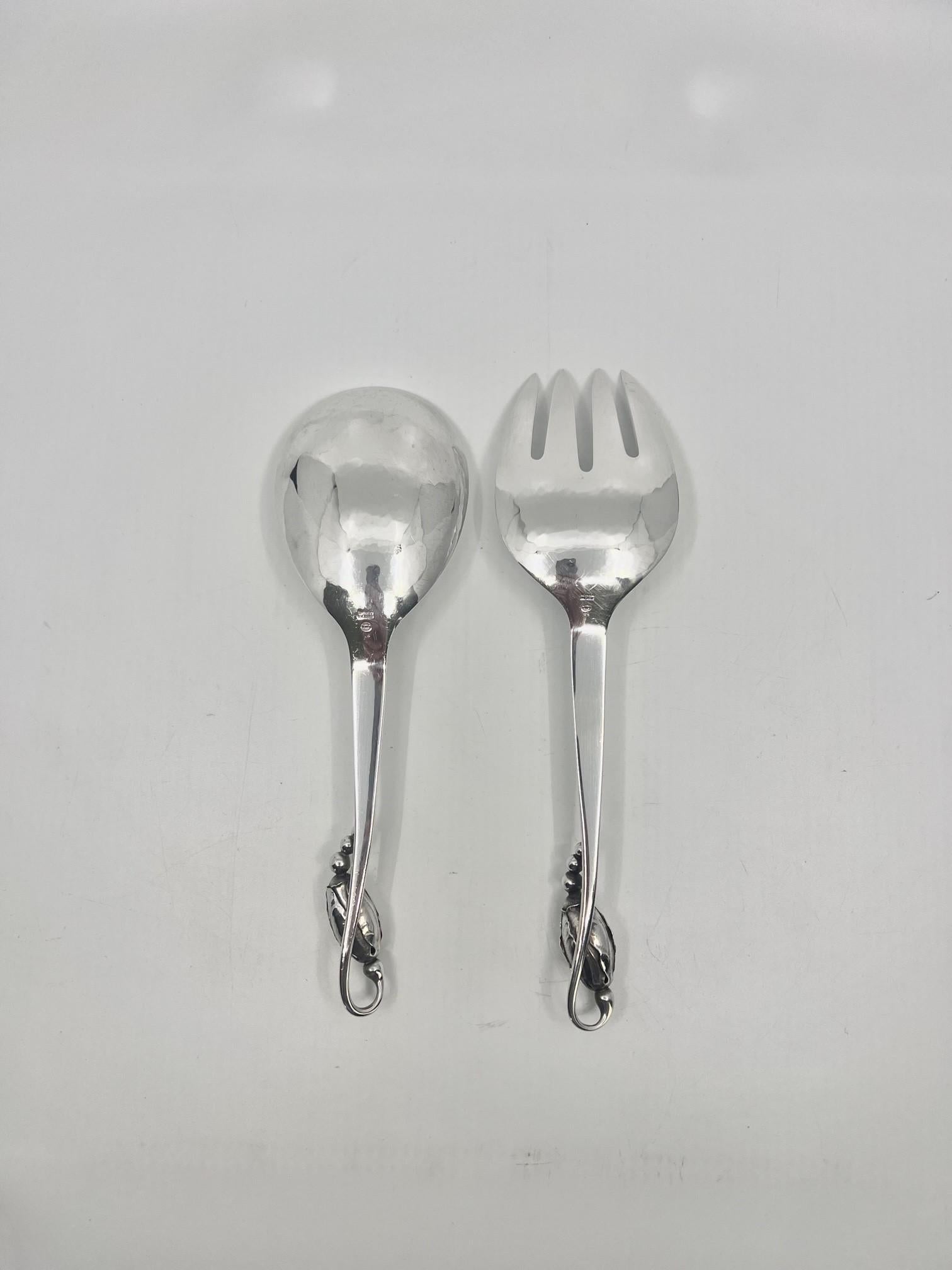 A vintage Georg Jensen Sterling Silver medium size serving set, items #113 & #114 in the Blossom pattern, design #84 by Georg Jensen from 1919.

Dimensions: The spoon measures 8 9/16″ (21.7cm) in length, the fork is 9 1/8″ (22,3cm), which attests to