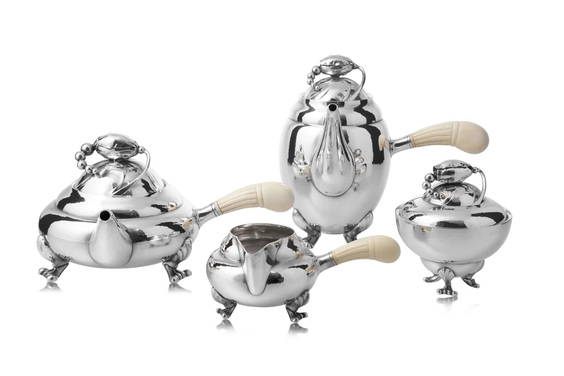 Un servizio da tè e caffè d'epoca di Georg Jensen in argento massiccio con manici in Ivory e vassoio abbinato (Design/One 2, 1905)

Questo squisito servizio da tè e caffè Georg Jensen Blossom, con manici in avorio, mette in mostra l'iconico design